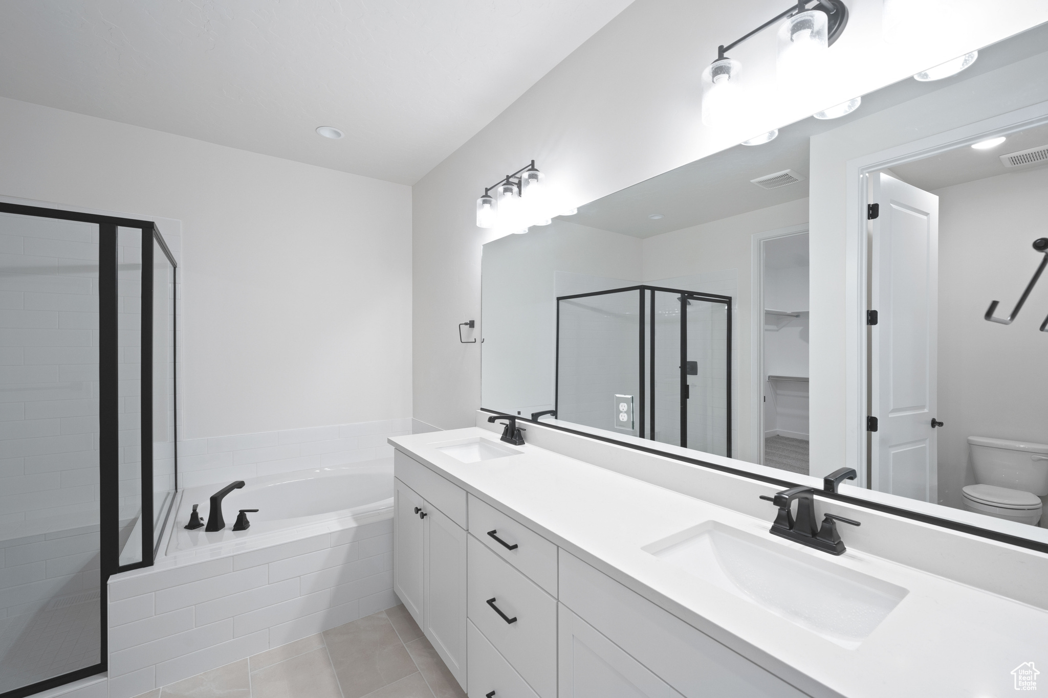 Full bathroom with a shower stall, a garden tub, double vanity, and a sink