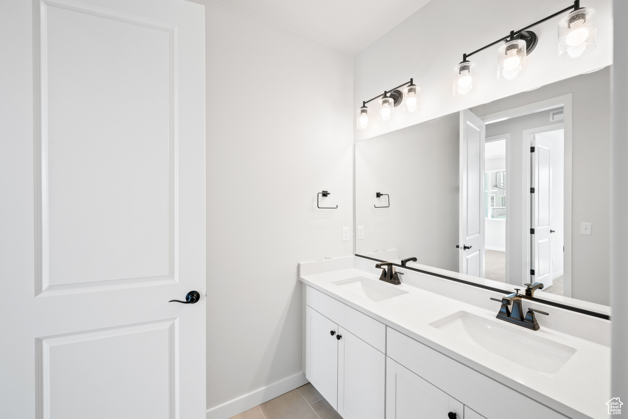 Full bath with a sink, baseboards, double vanity, and tile patterned floors