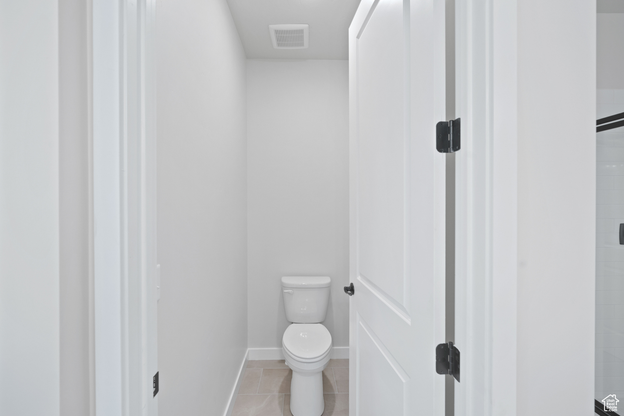 Bathroom with visible vents, toilet, a tile shower, tile patterned flooring, and baseboards