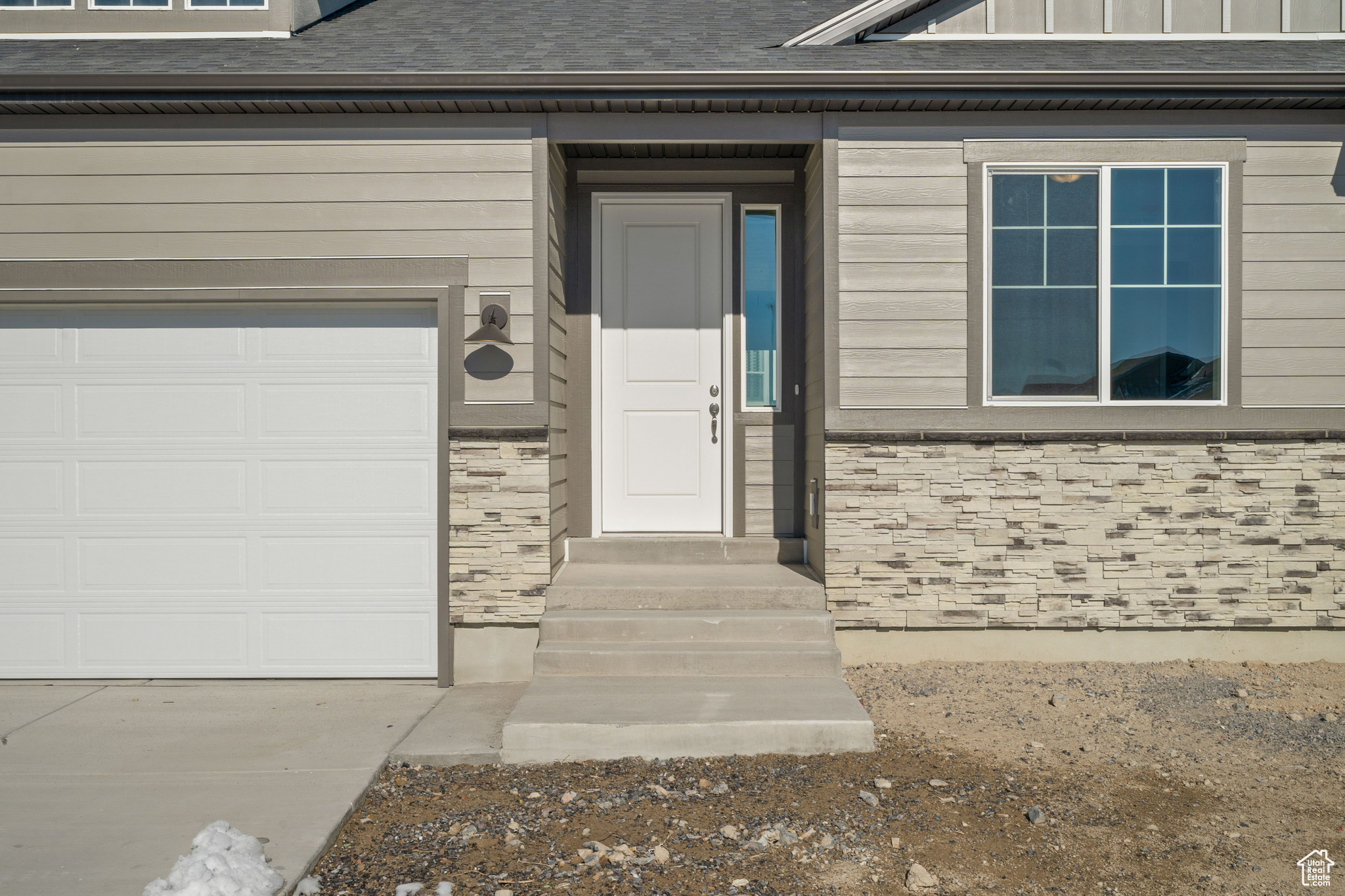 Entrance to property with a garage and roof with shingles