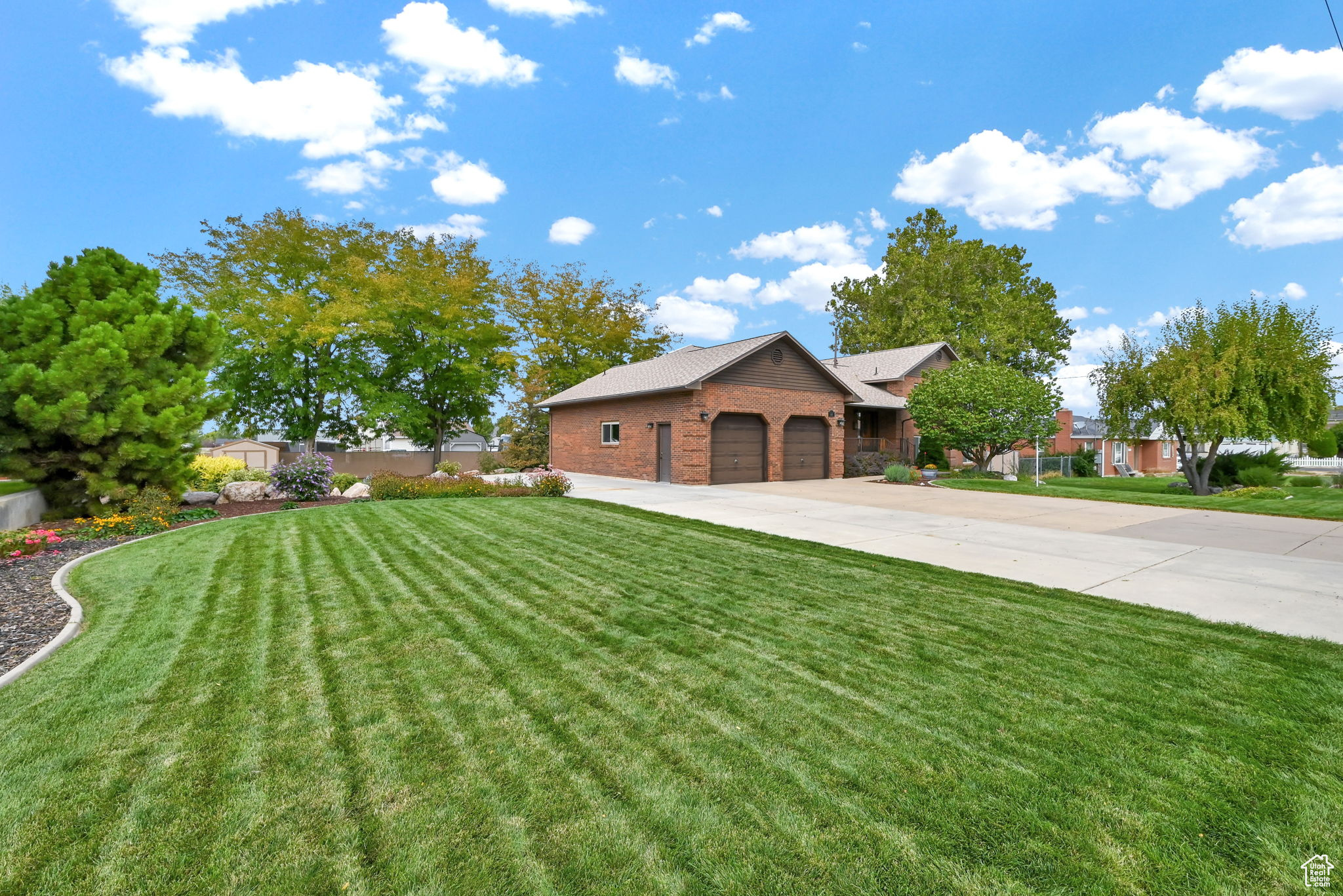 View of front of property with a garage, brick siding, concrete driveway, and a front lawn