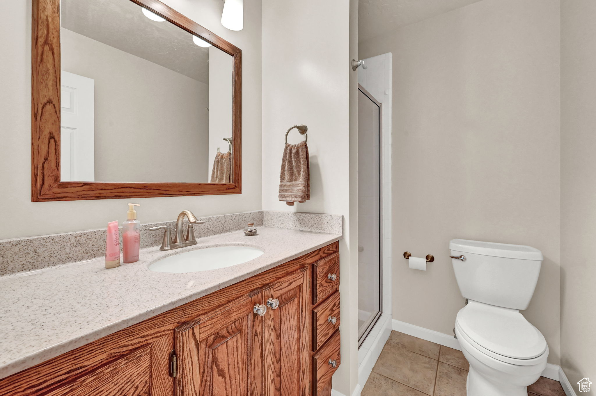 Full bathroom with baseboards, toilet, a stall shower, tile patterned floors, and vanity