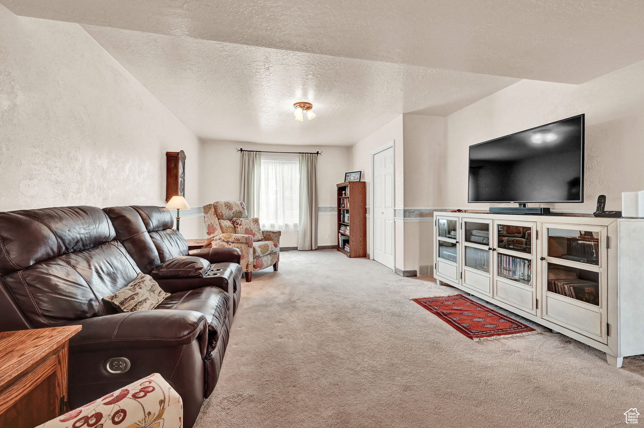 Carpeted living room with a textured ceiling