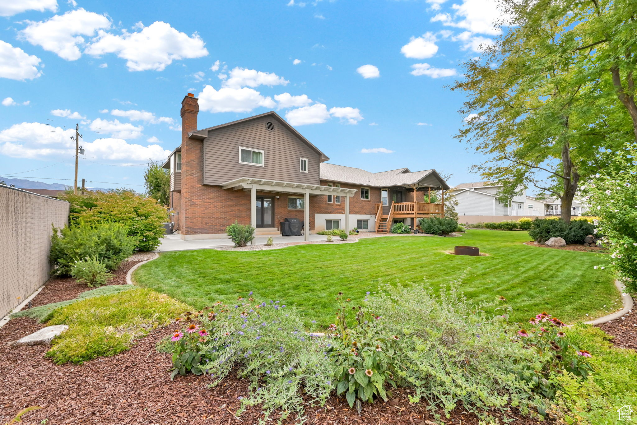 Rear view of property with fence, a pergola, a chimney, a patio area, and brick siding