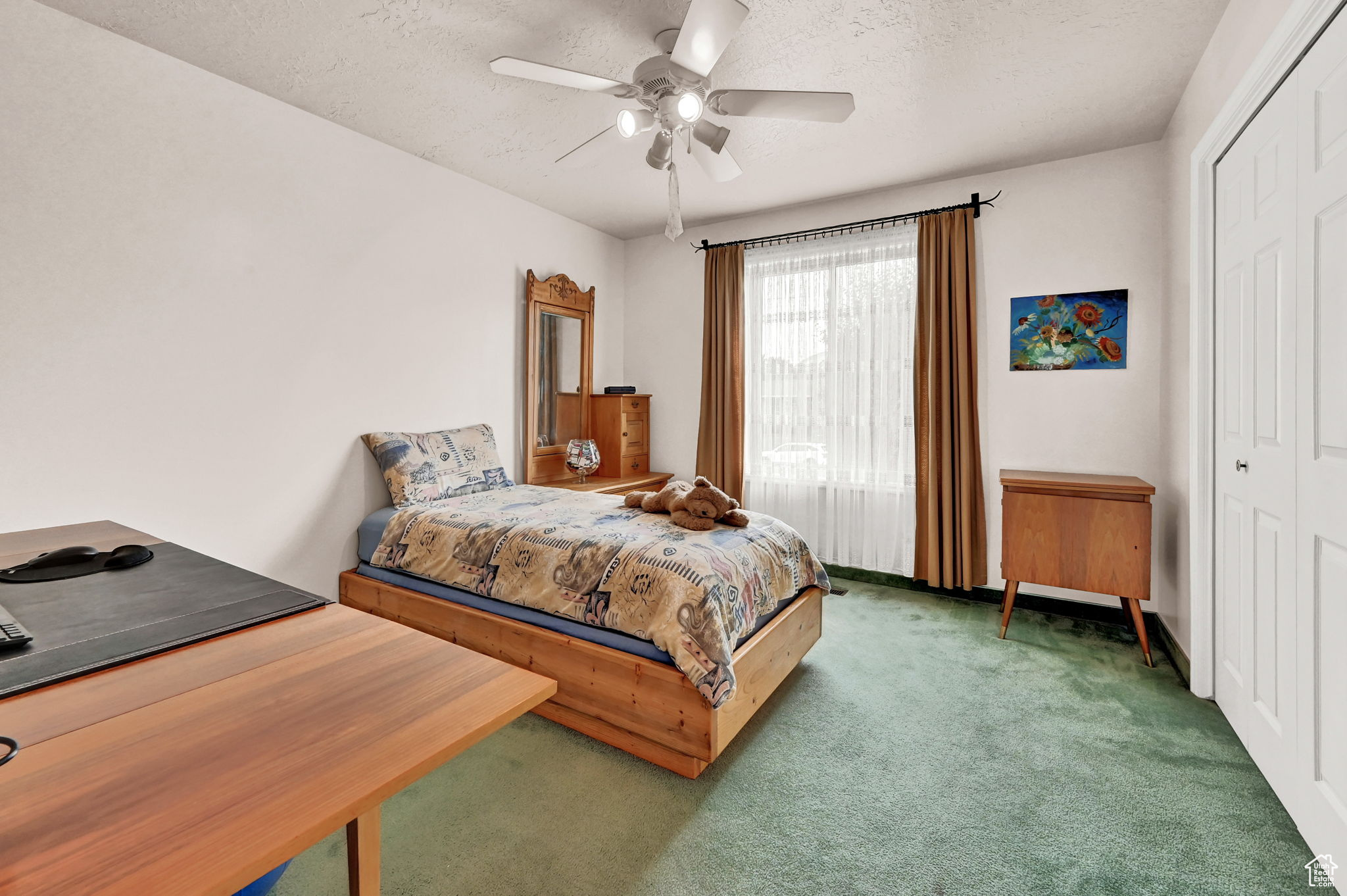 Carpeted bedroom with a closet, a textured ceiling, and ceiling fan