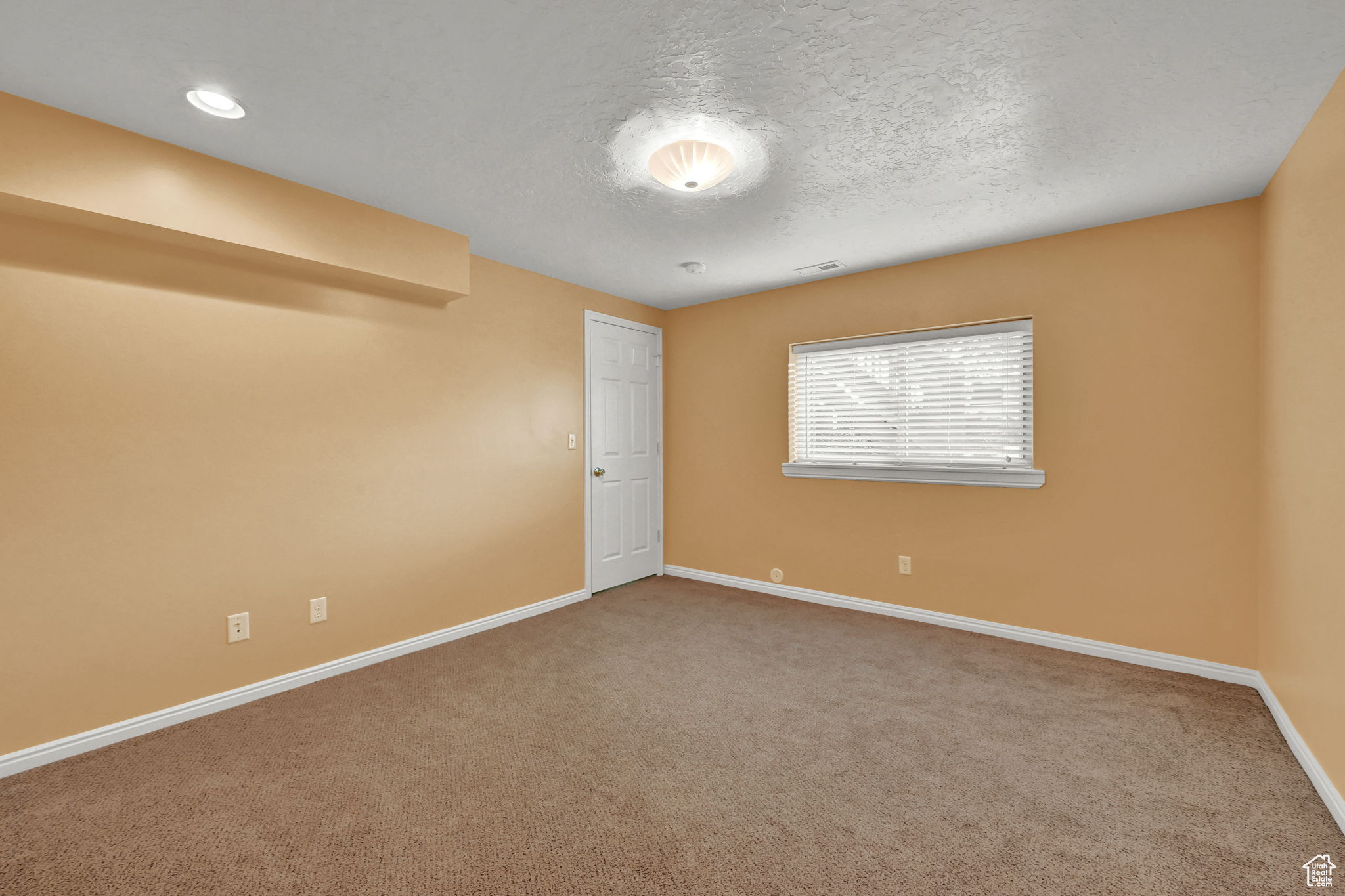 Carpeted spare room featuring visible vents, baseboards, and a textured ceiling