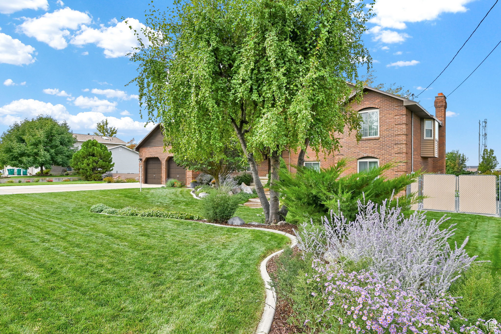 Obstructed view of property with a front yard, fence, driveway, a chimney, and brick siding