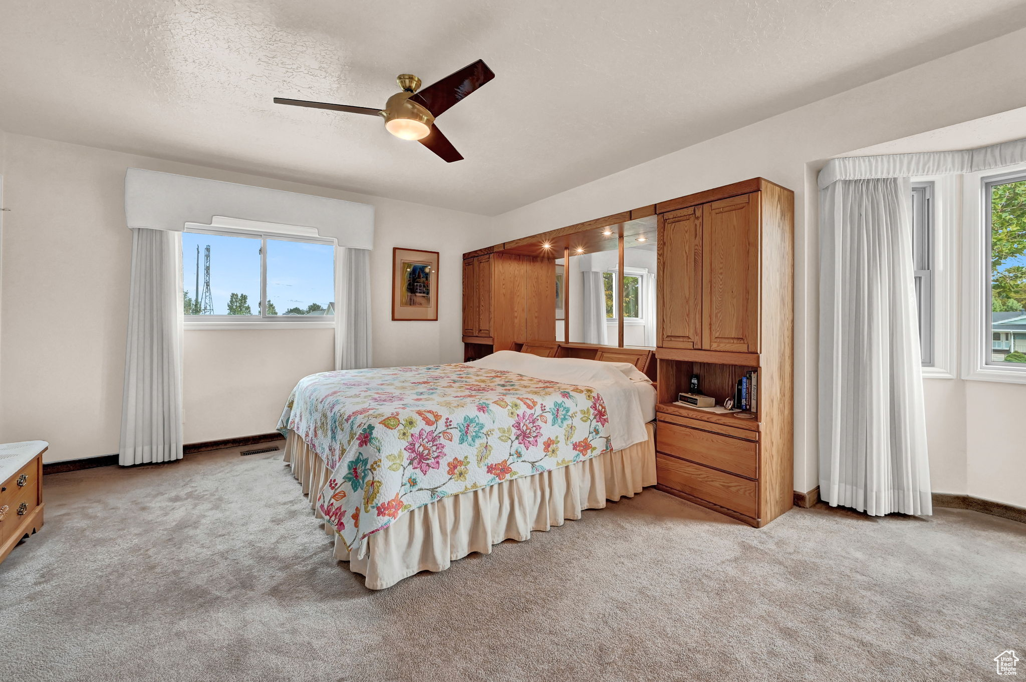 Bedroom with ceiling fan, light colored carpet, baseboards, and a textured ceiling