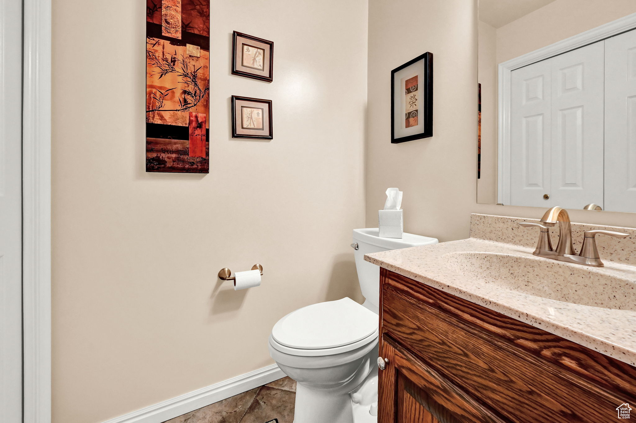 Half bath featuring toilet, vanity, and baseboards