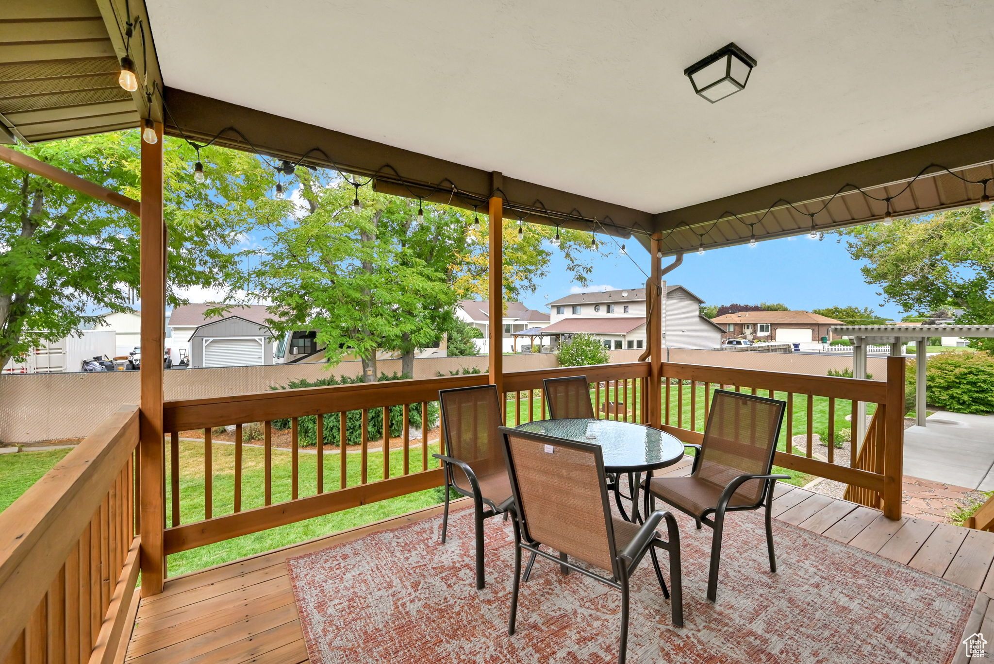 Wooden terrace featuring fence, a residential view, outdoor dining area, a yard, and a pergola