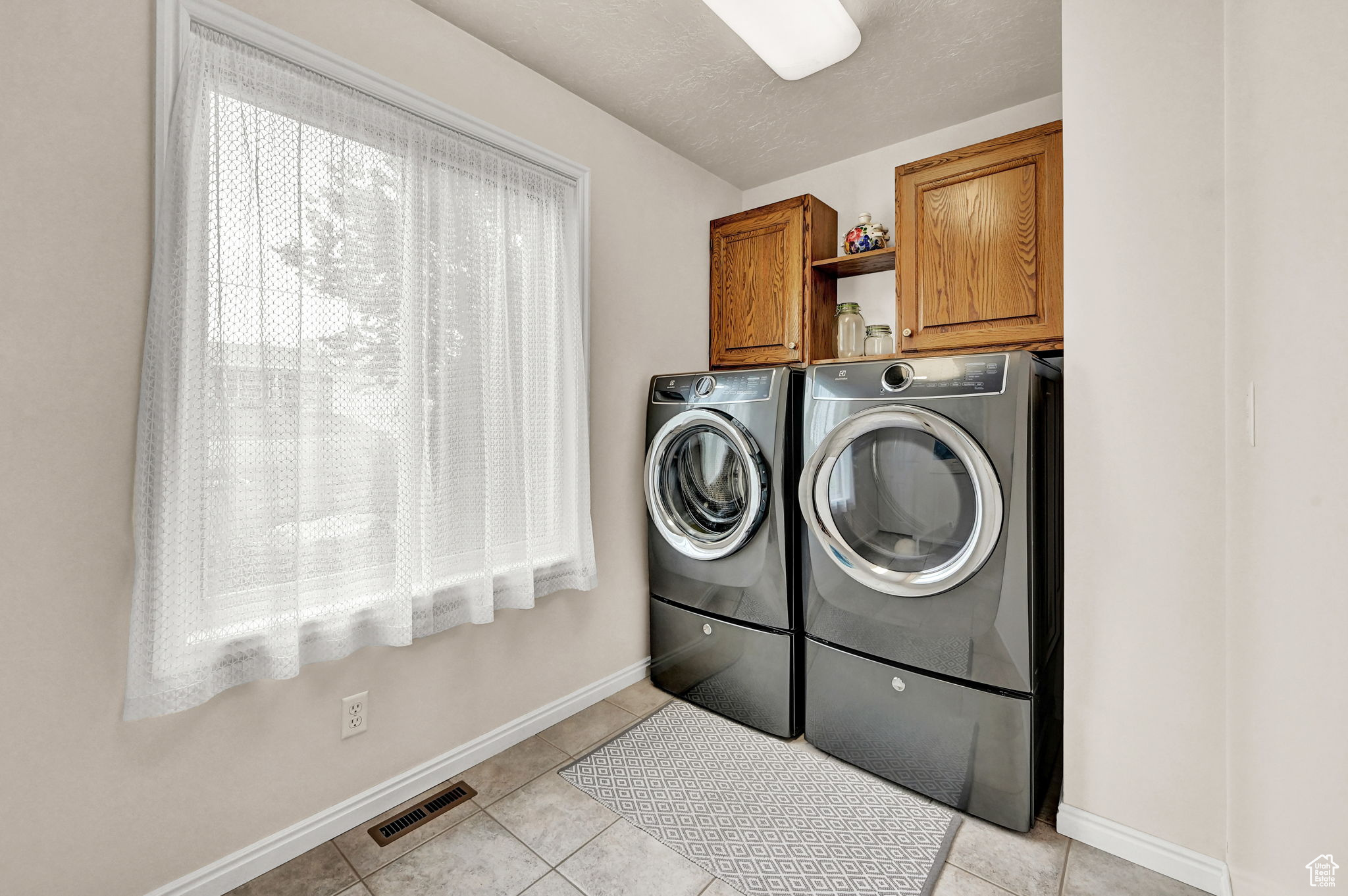 Laundry area featuring visible vents, cabinet space, baseboards, and washing machine and dryer