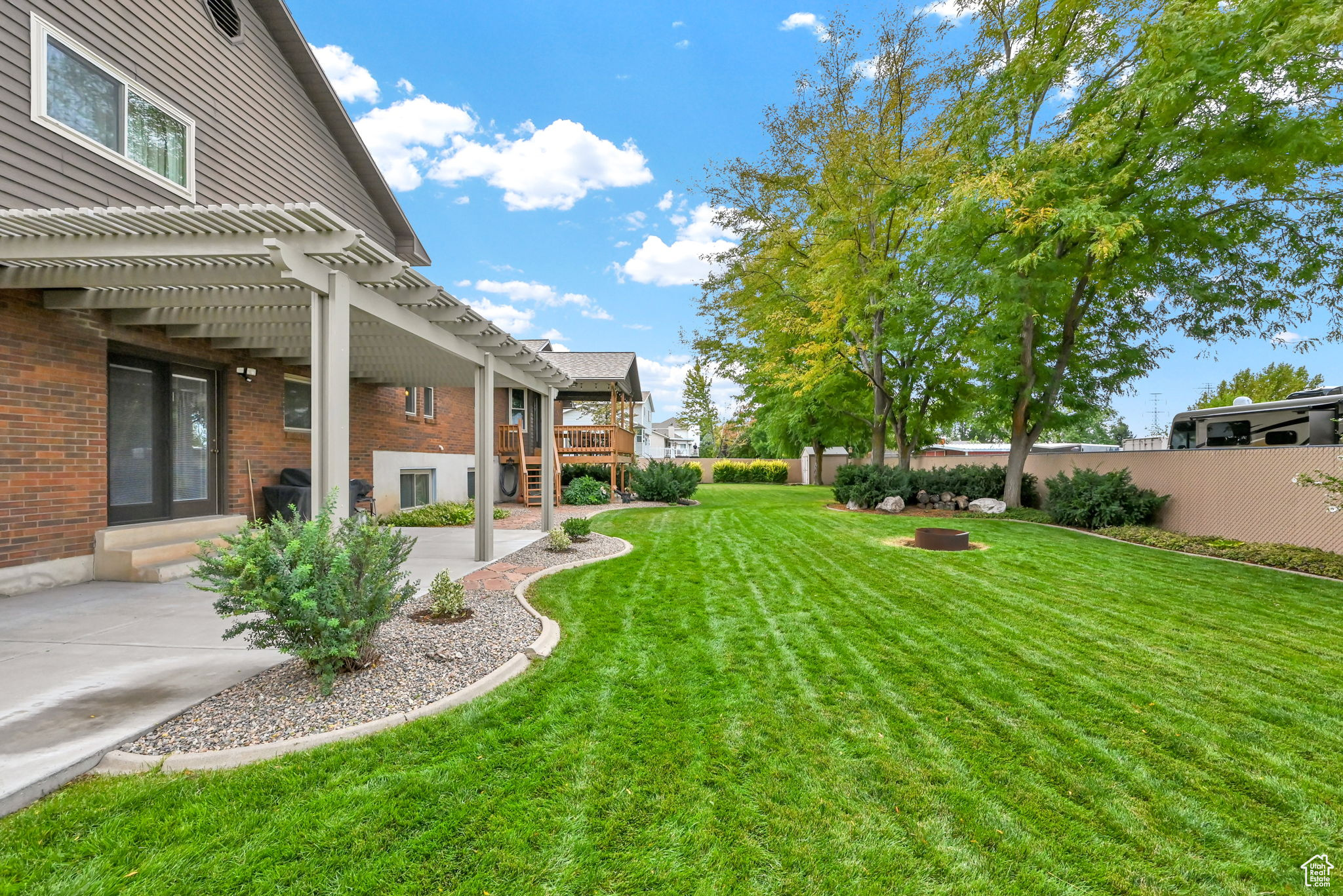 View of yard with a deck, a patio area, fence, and a pergola