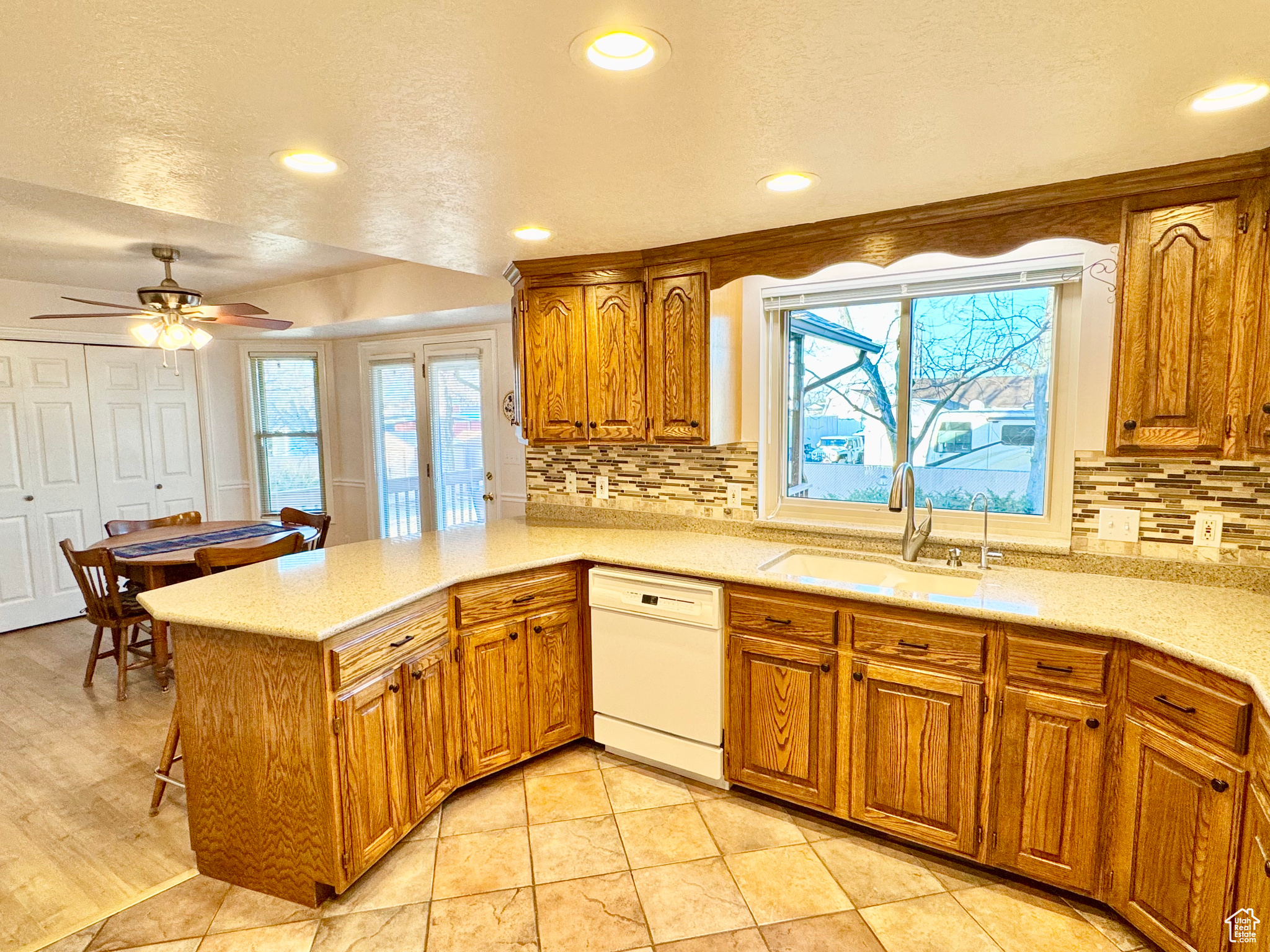 Kitchen with brown cabinets, a sink, plenty of natural light, a peninsula, and dishwasher