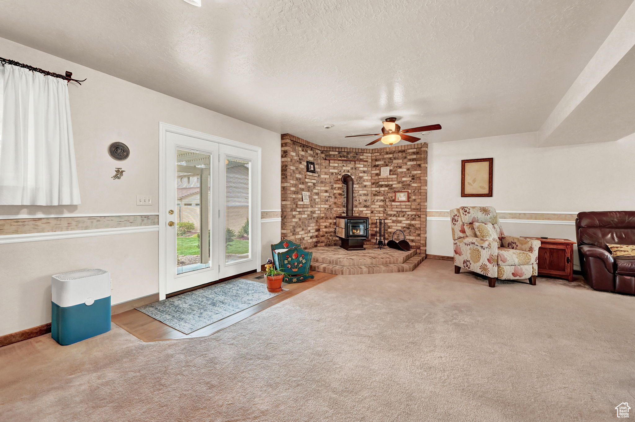 Living room featuring carpet, a wood stove, and a textured ceiling