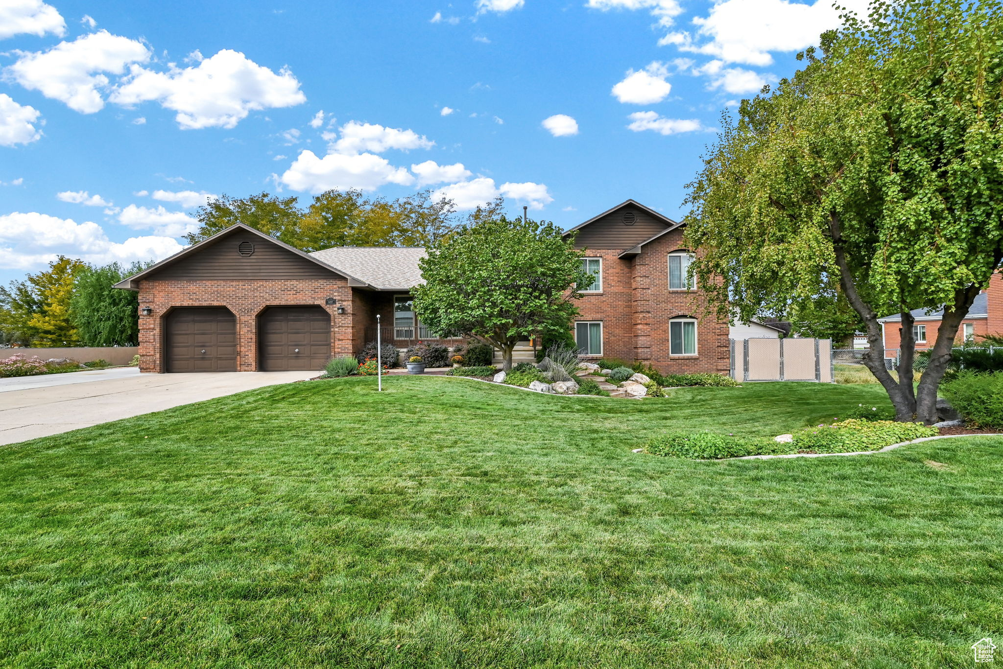 View of front of home with concrete driveway, an attached garage, brick siding, and a front yard