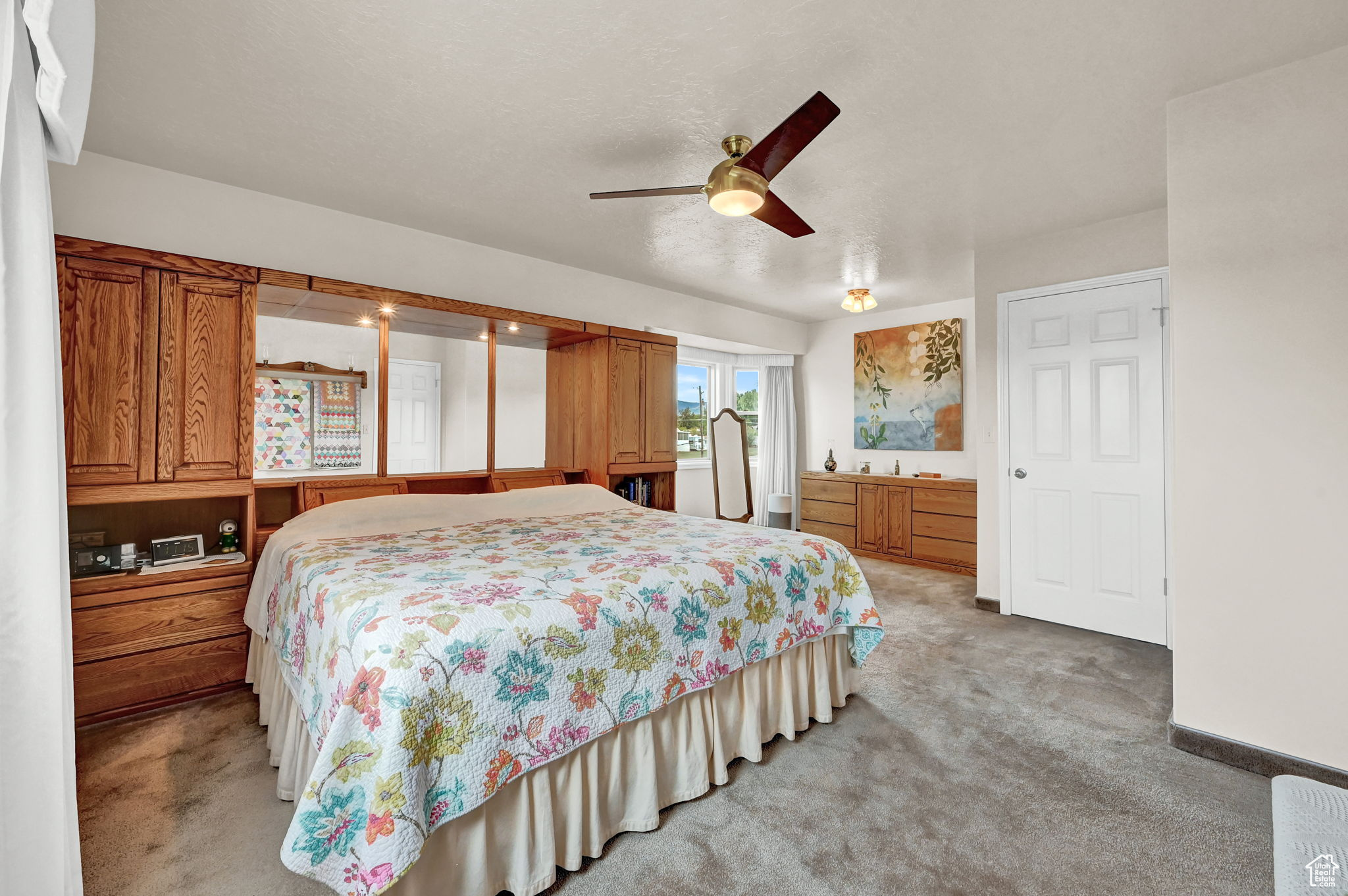 Bedroom featuring baseboards, light carpet, a textured ceiling, and a ceiling fan