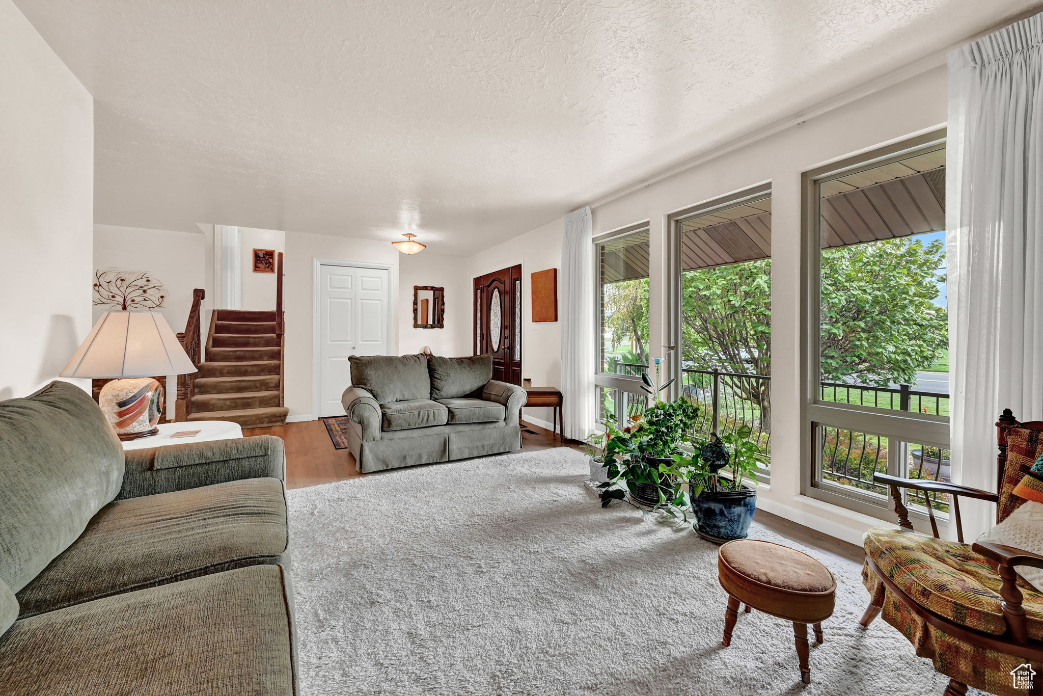 Living area with plenty of natural light, a textured ceiling, stairs, and wood finished floors