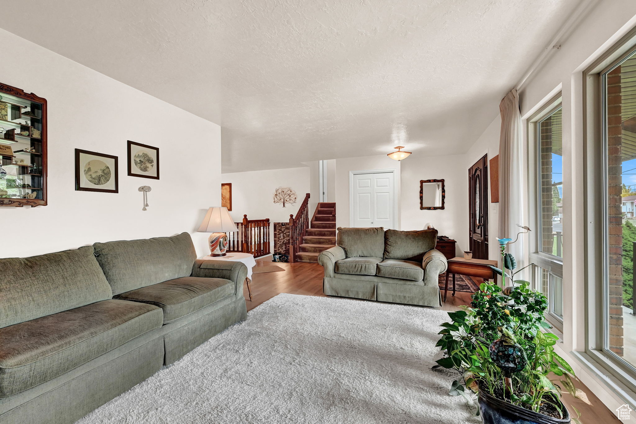 Living room with stairs, plenty of natural light, wood finished floors, and a textured ceiling