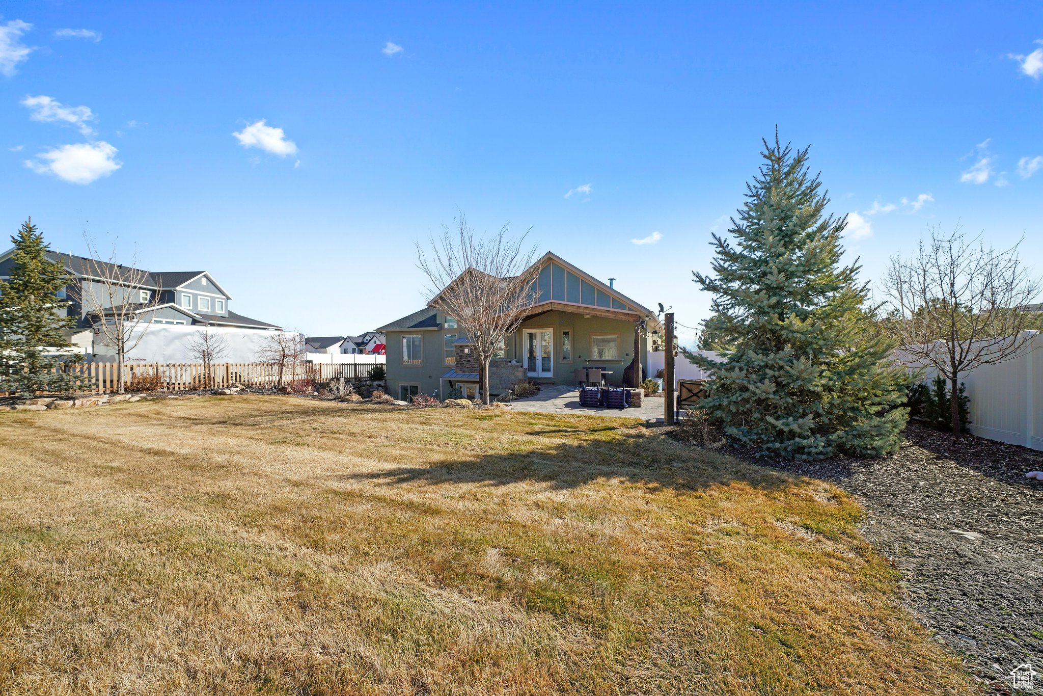 Rear view of house featuring a lawn, a patio, and fence