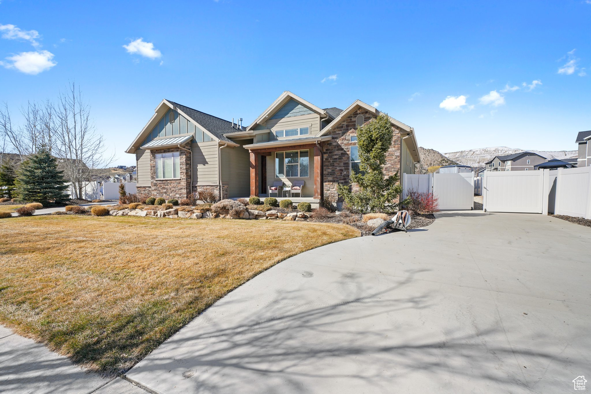 View of front of property featuring a front yard, a gate, fence, stone siding, and board and batten siding