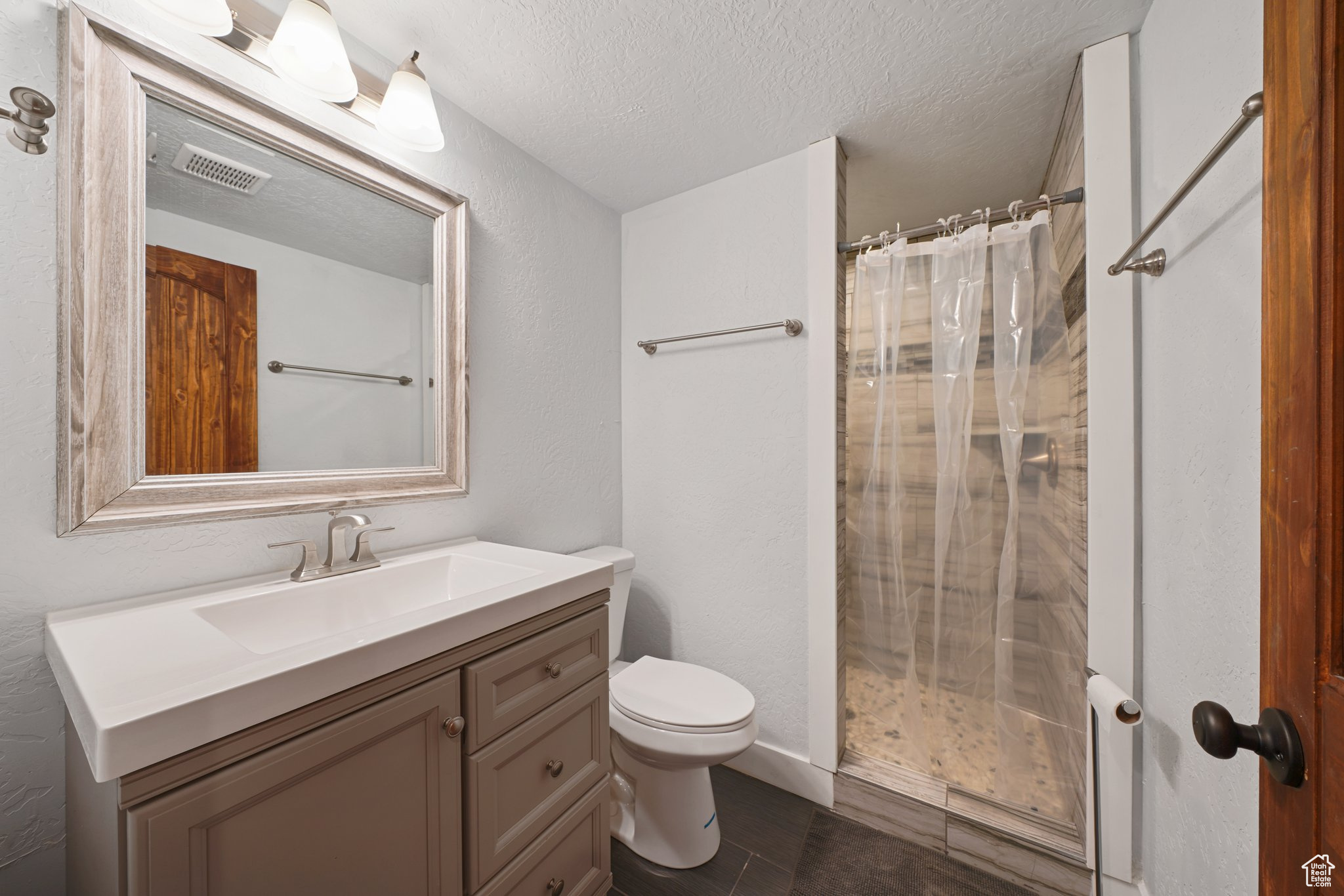 Bathroom with visible vents, toilet, a textured ceiling, a shower with shower curtain, and vanity