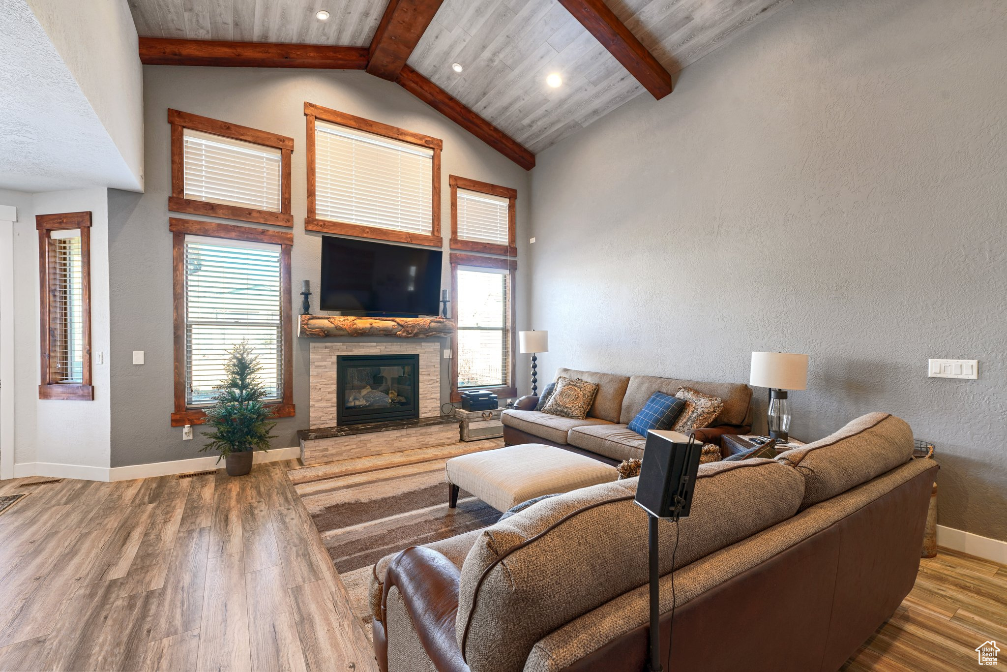 Living area with beam ceiling, a fireplace, baseboards, and wood finished floors