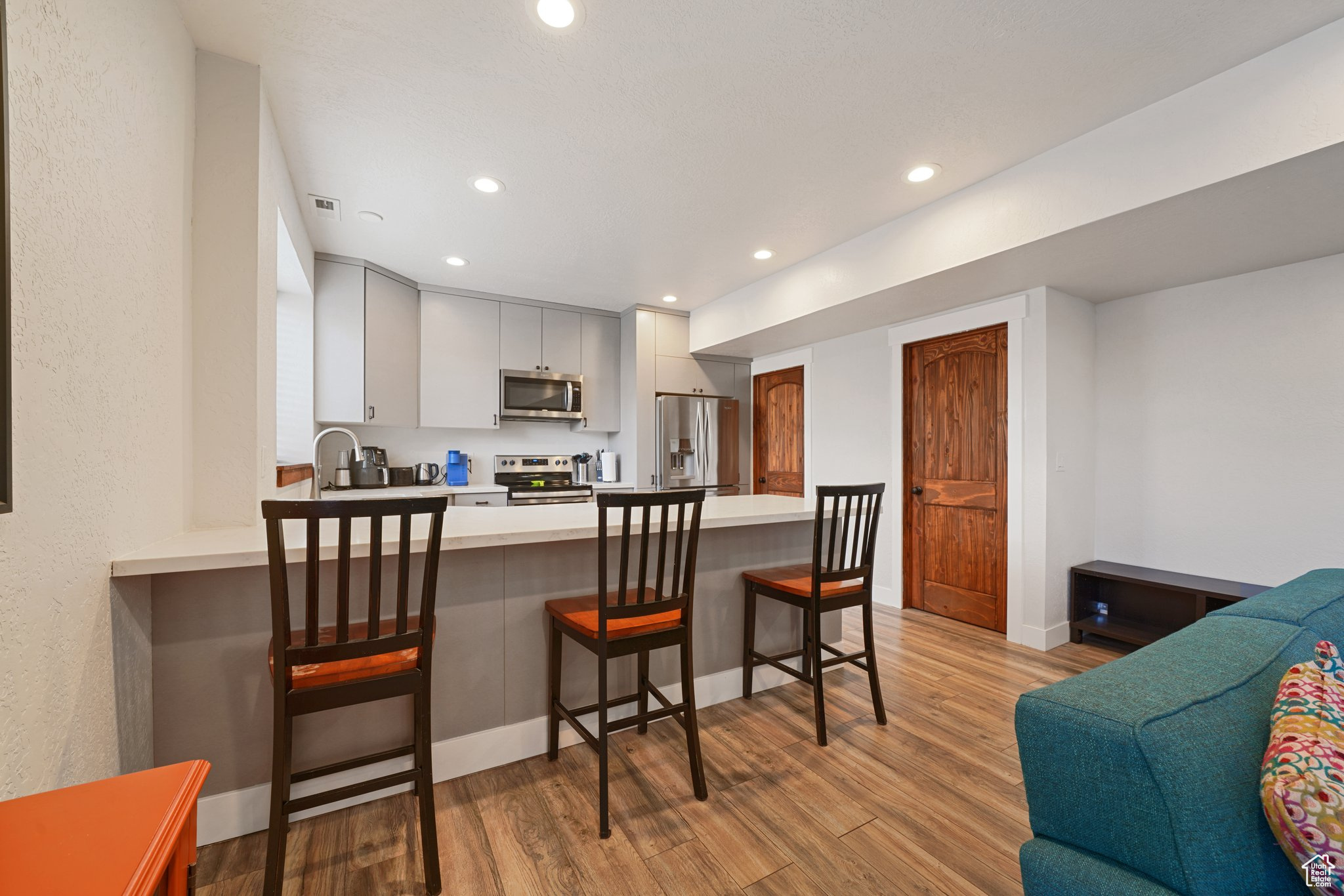 Kitchen featuring light wood-type flooring, recessed lighting, stainless steel appliances, a peninsula, and light countertops