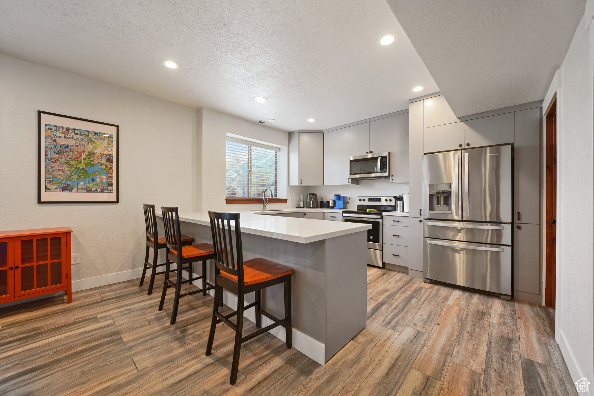 Kitchen with a breakfast bar, a peninsula, light wood finished floors, and appliances with stainless steel finishes