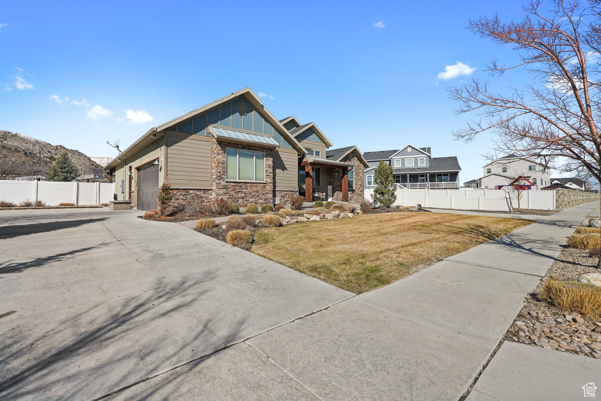 Craftsman inspired home with board and batten siding, fence, concrete driveway, stone siding, and an attached garage