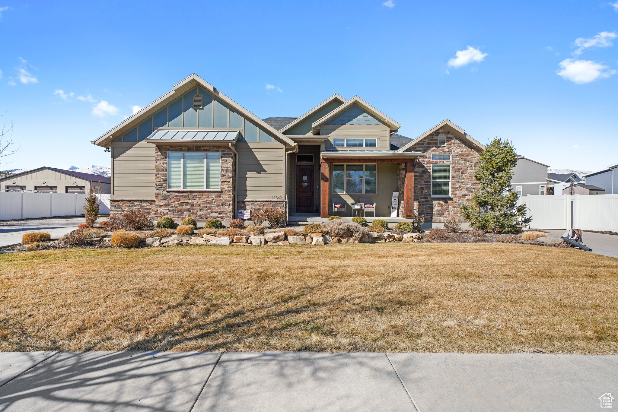 Craftsman house featuring fence, a porch, a front lawn, stone siding, and board and batten siding