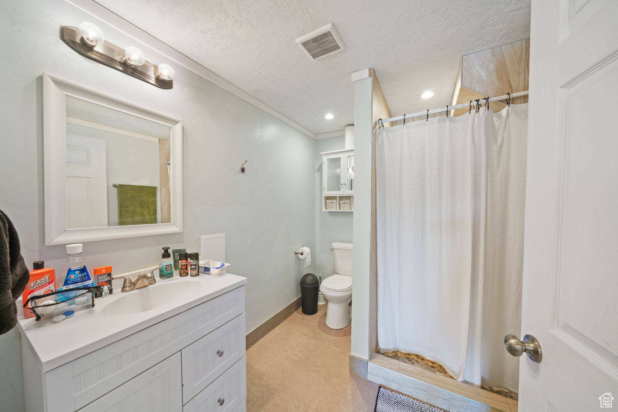 Bathroom with visible vents, toilet, a textured ceiling, baseboards, and vanity