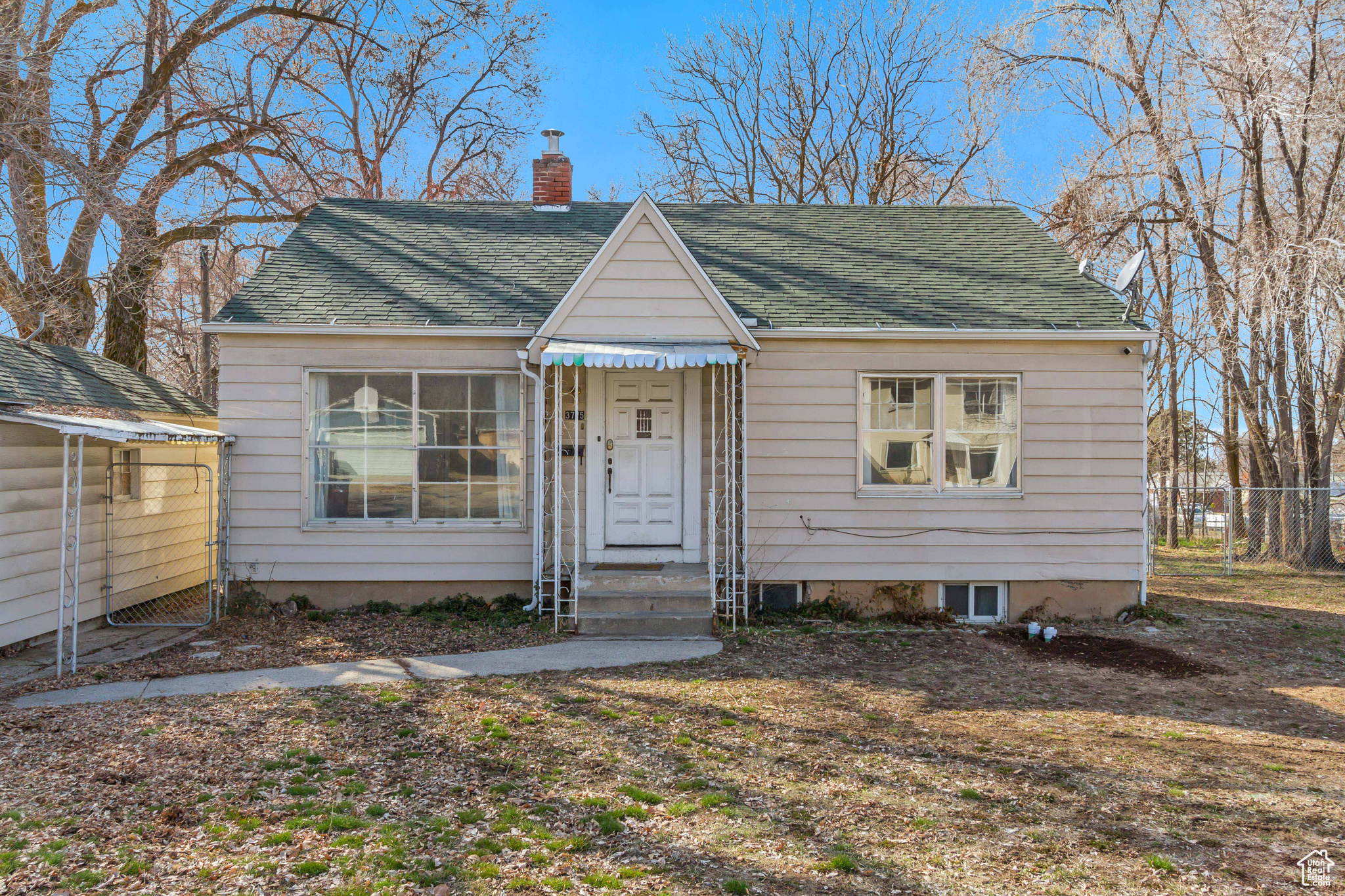 Bungalow-style home with fence, roof with shingles, and a chimney