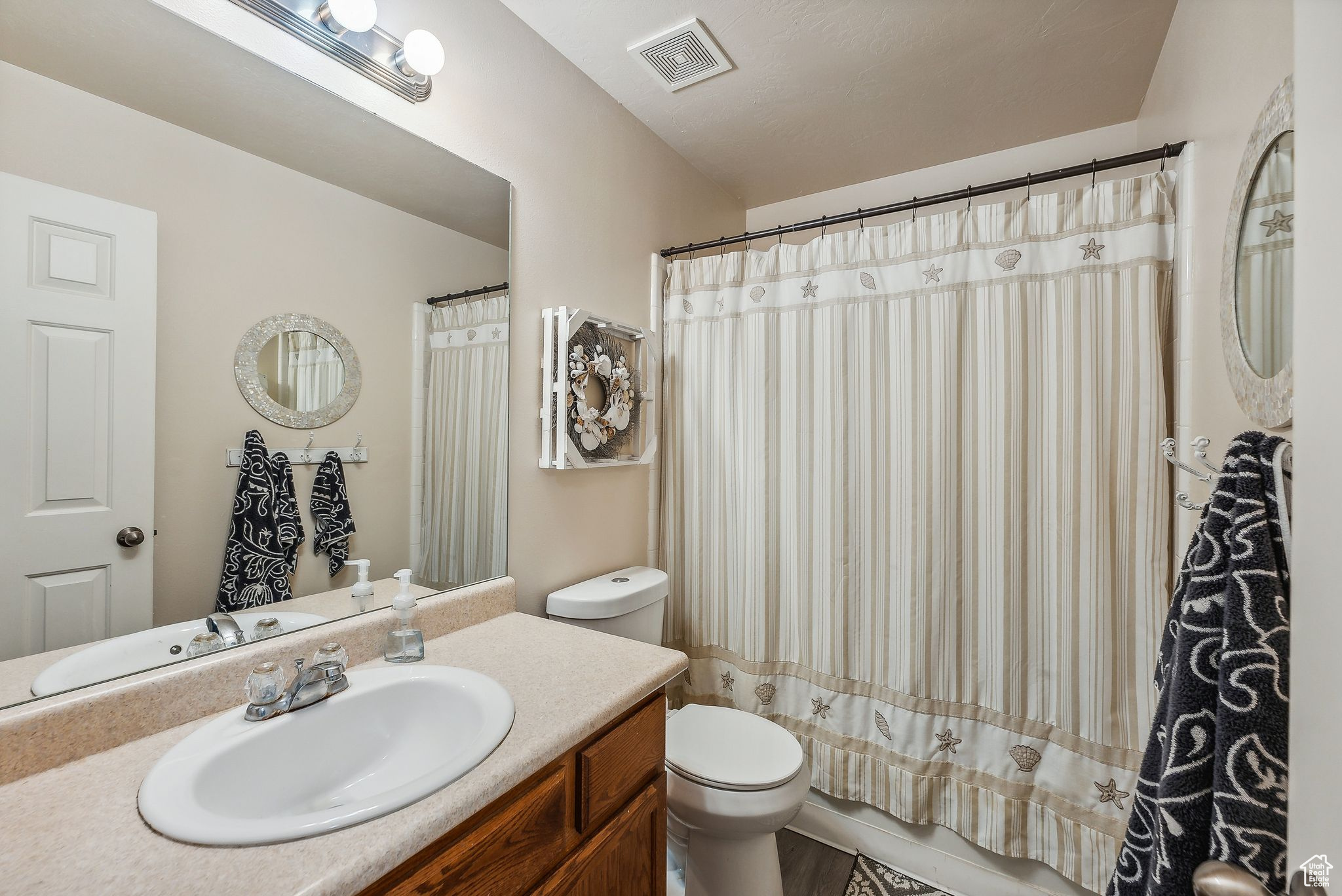 Full bath featuring visible vents, curtained shower, toilet, and vanity