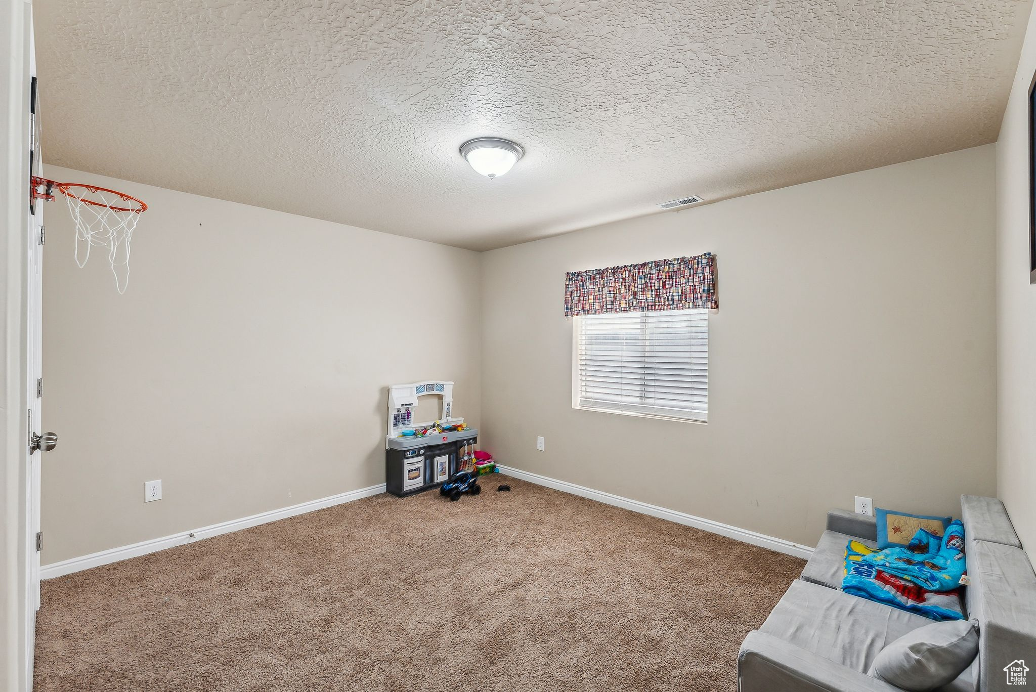 Playroom featuring a textured ceiling, baseboards, and carpet floors