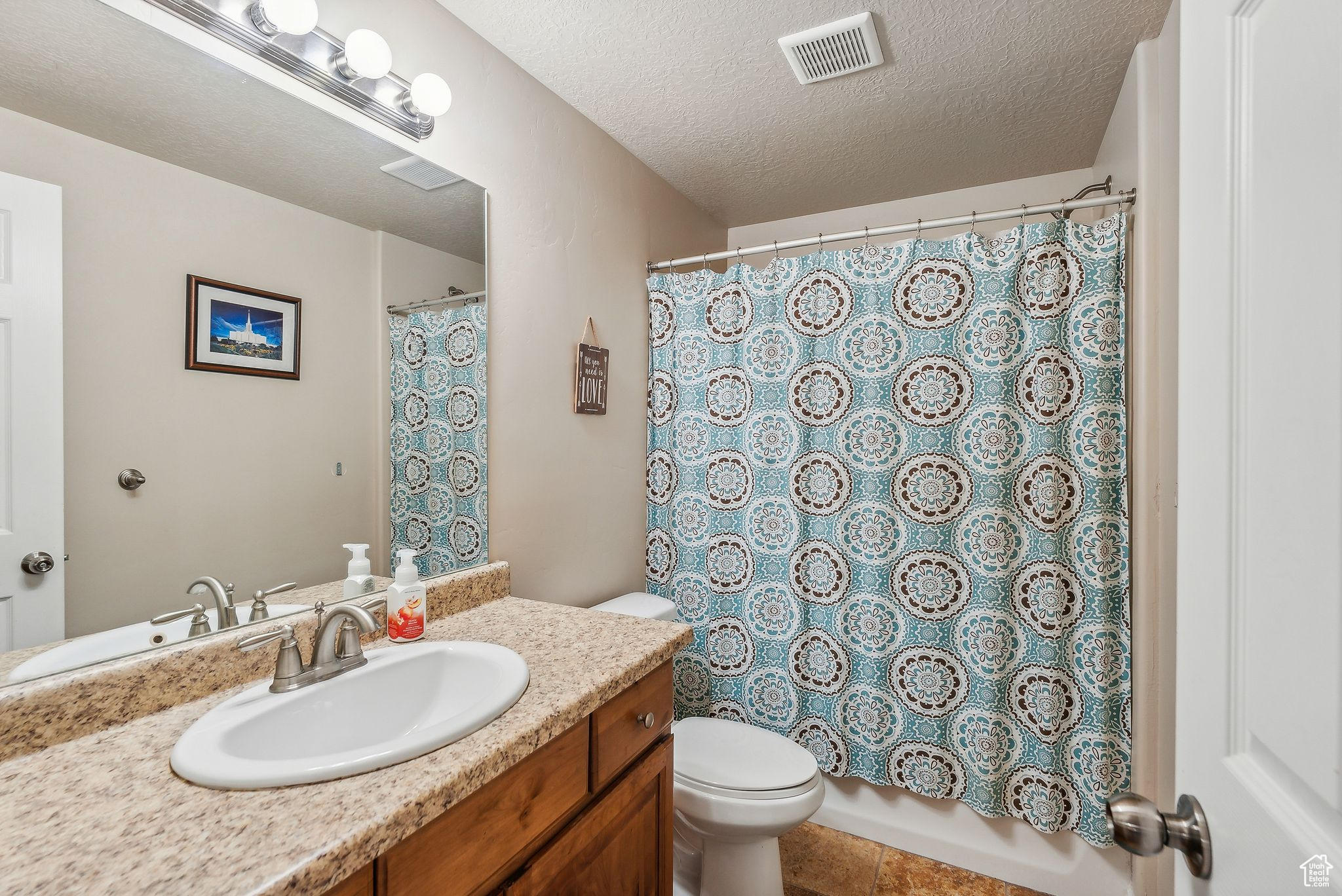 Full bath with tile patterned floors, visible vents, toilet, a textured ceiling, and vanity