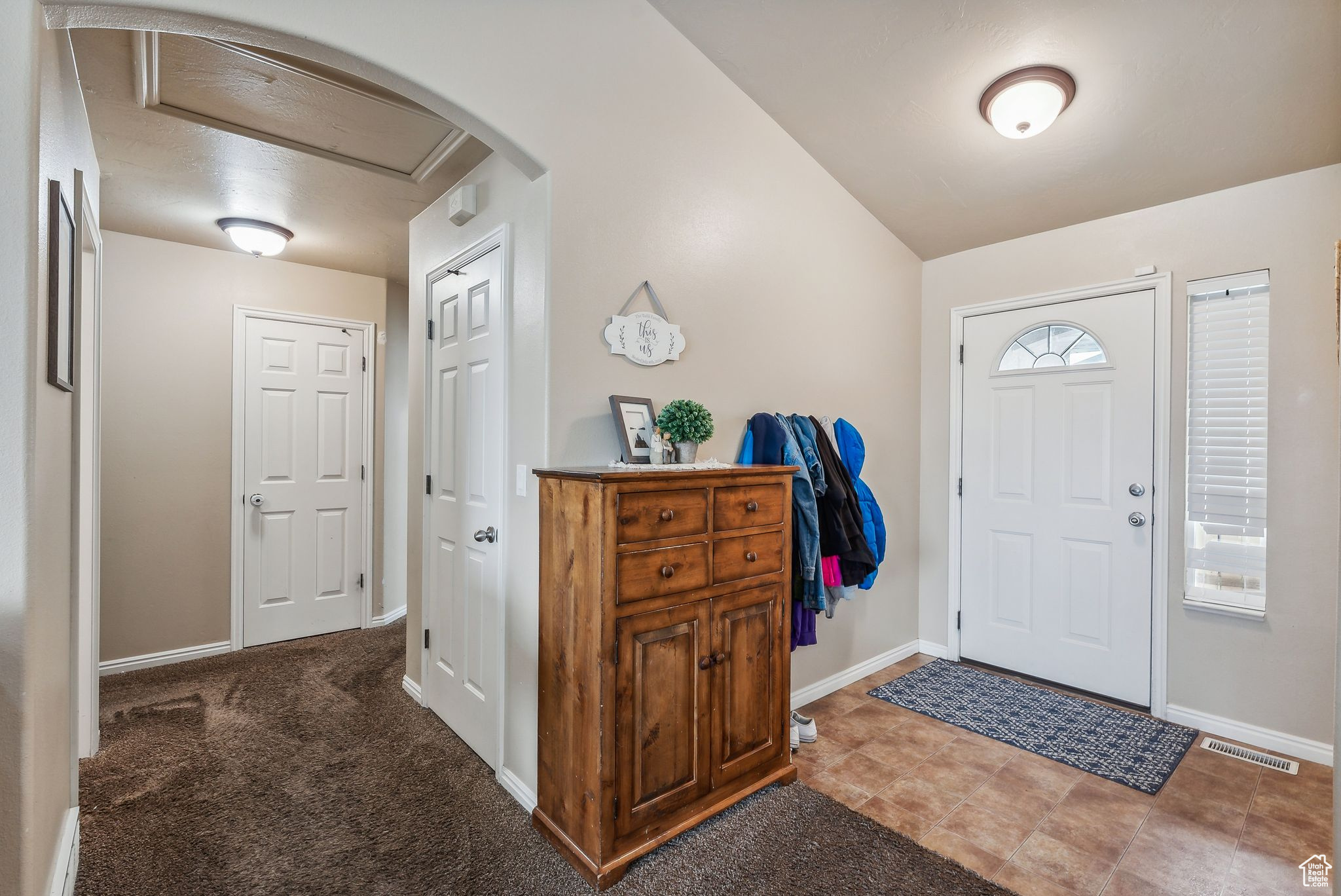 Entrance foyer featuring arched walkways, visible vents, baseboards, and vaulted ceiling