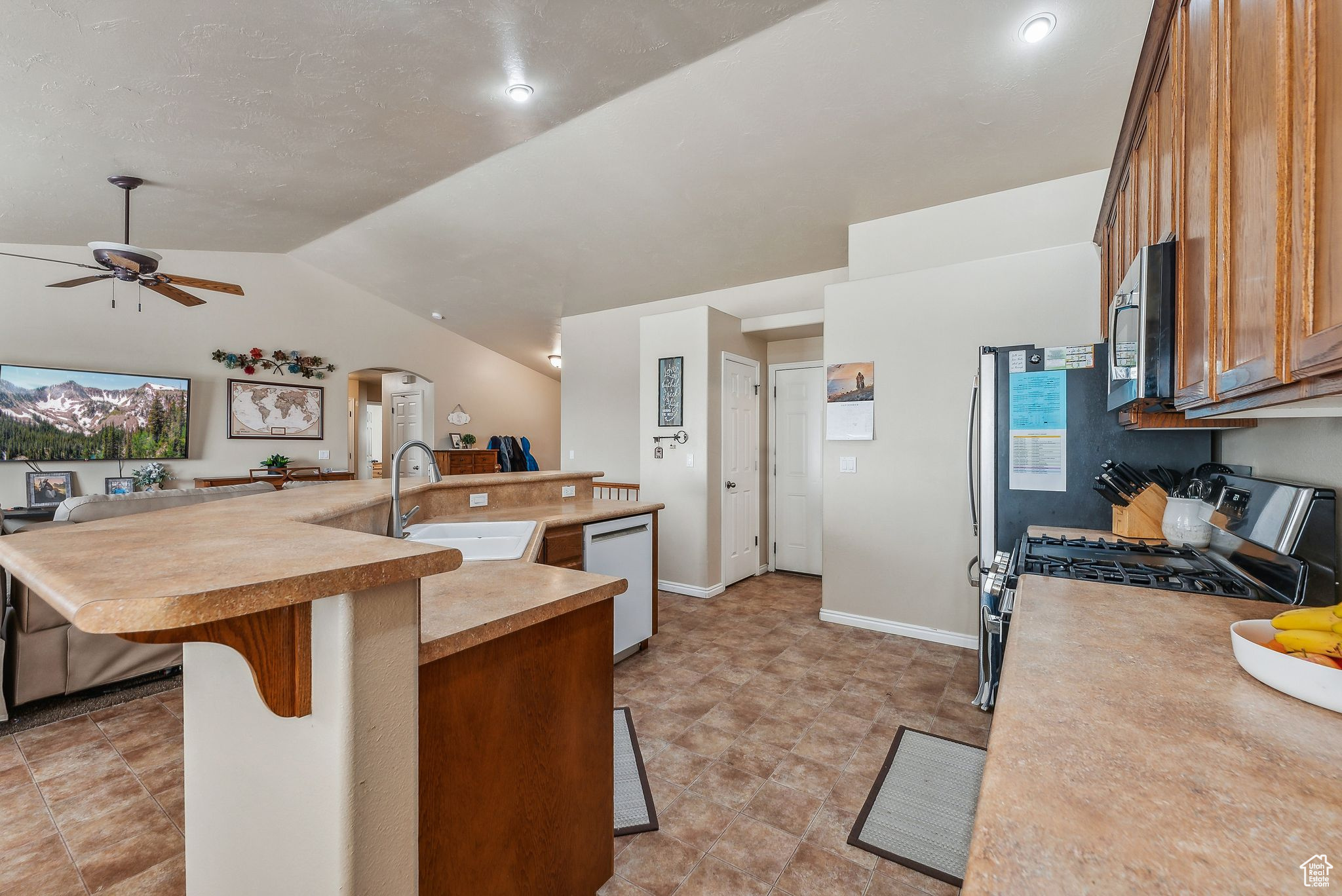 Kitchen with a kitchen bar, a large island, appliances with stainless steel finishes, and a sink