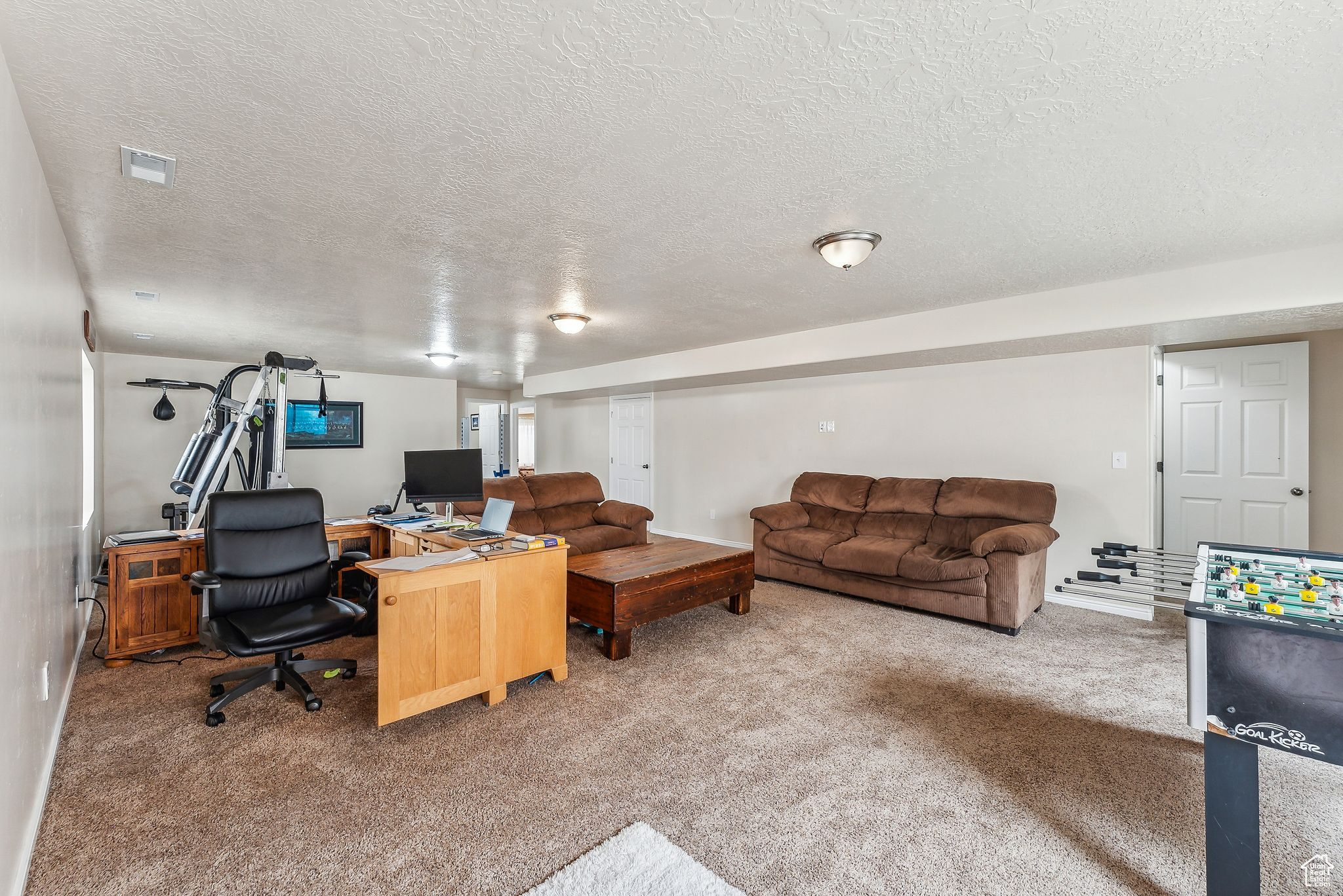 Office area featuring visible vents, carpet floors, a textured ceiling, and baseboards