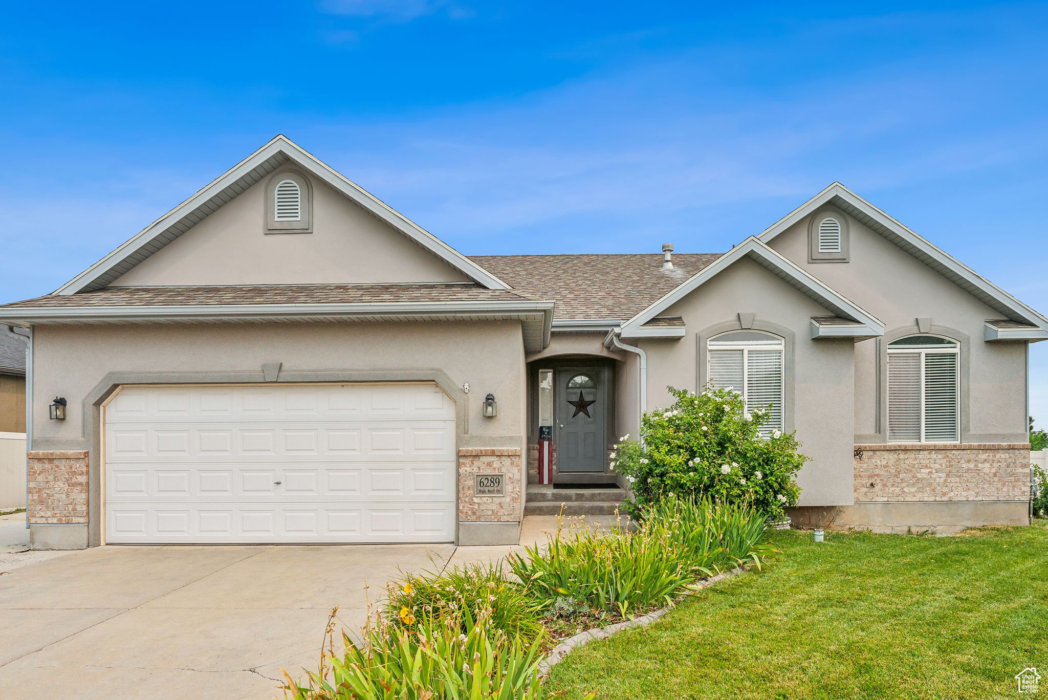 Single story home featuring stucco siding, a front lawn, concrete driveway, a garage, and brick siding