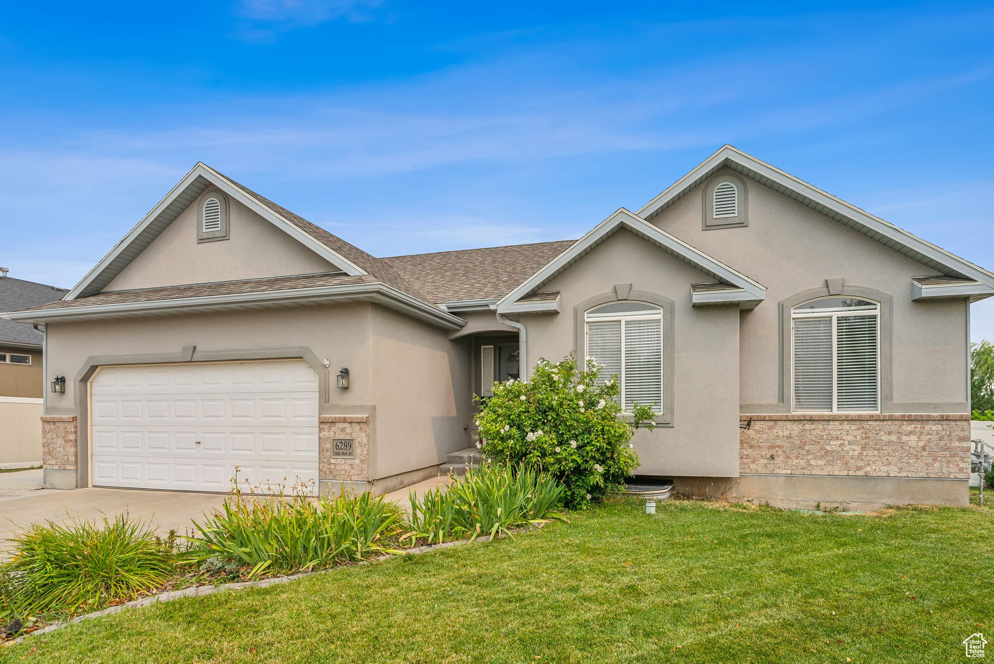 Single story home featuring concrete driveway, a front yard, roof with shingles, stucco siding, and a garage