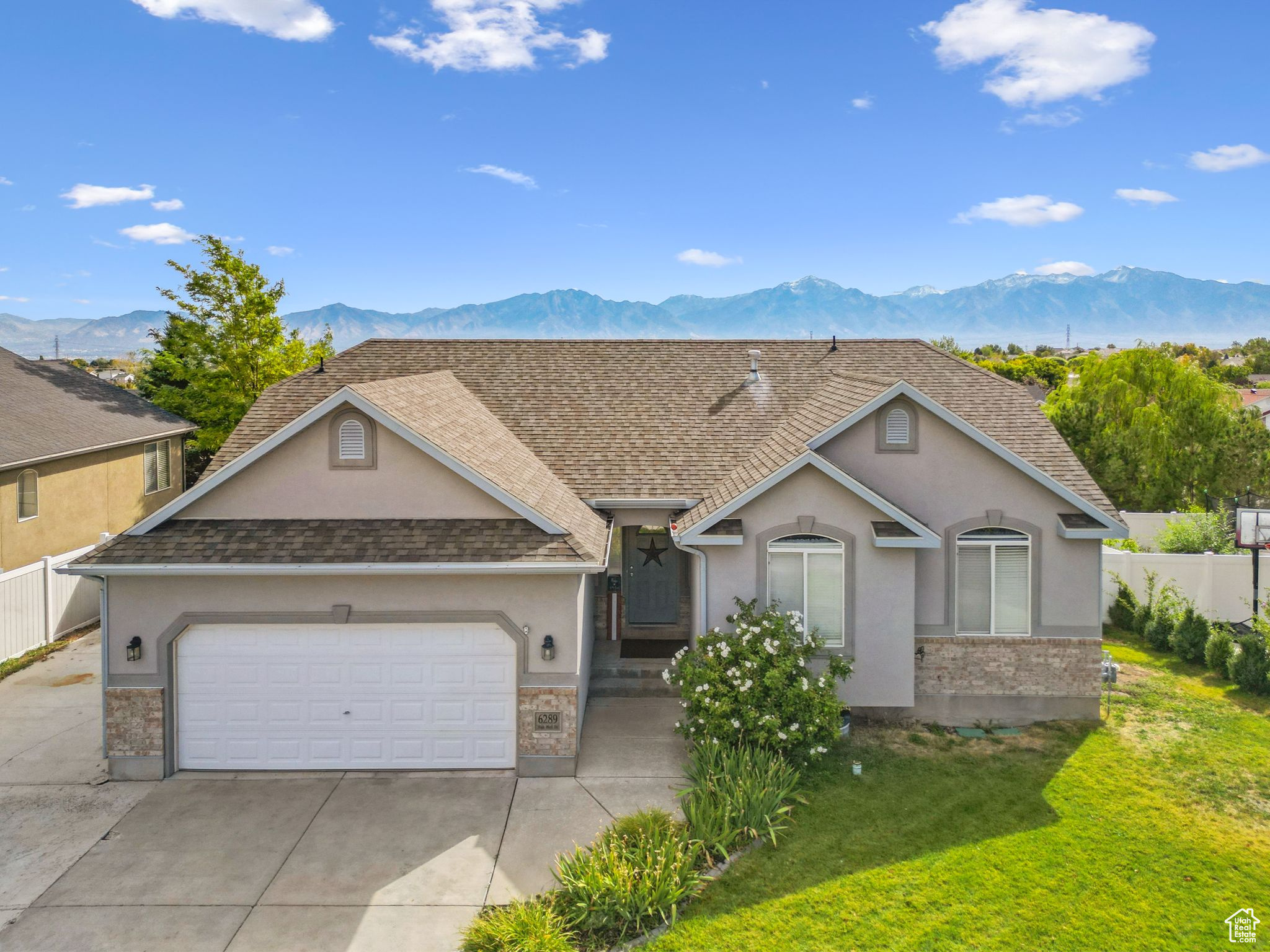 View of front of house with fence, an attached garage, a front lawn, concrete driveway, and a mountain view