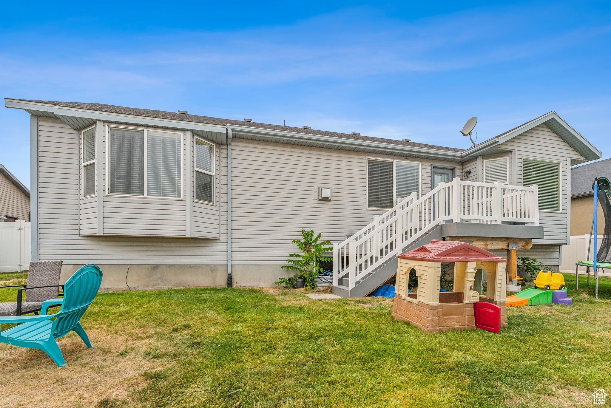 Back of house with a yard, a trampoline, a deck, and stairway