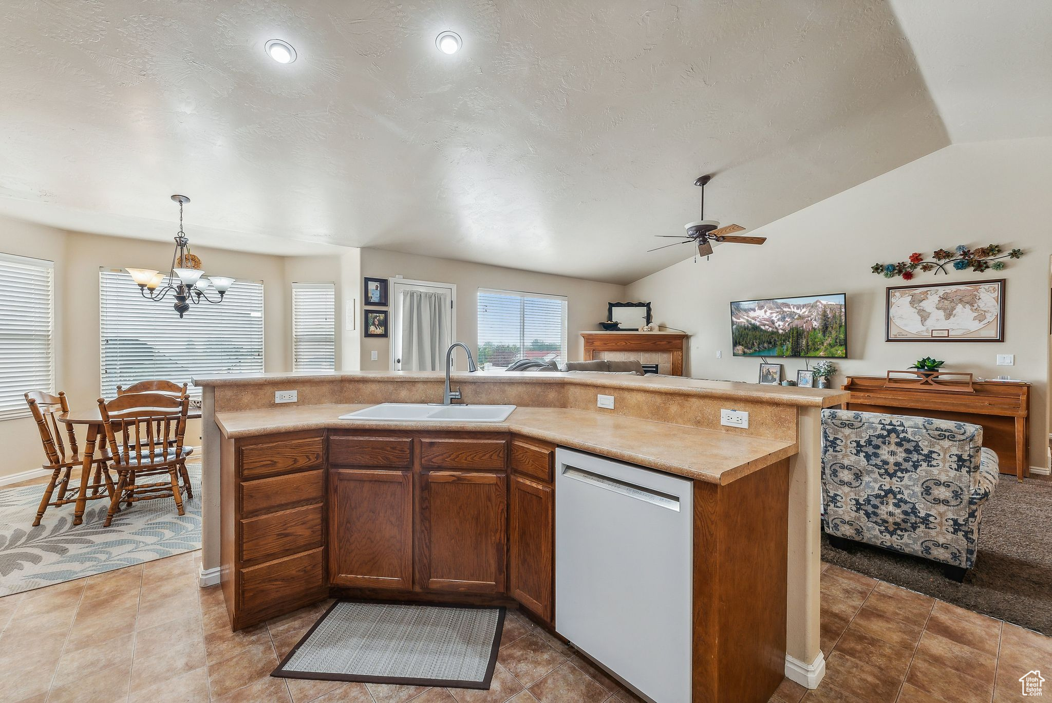 Kitchen featuring lofted ceiling, a sink, light countertops, dishwasher, and open floor plan