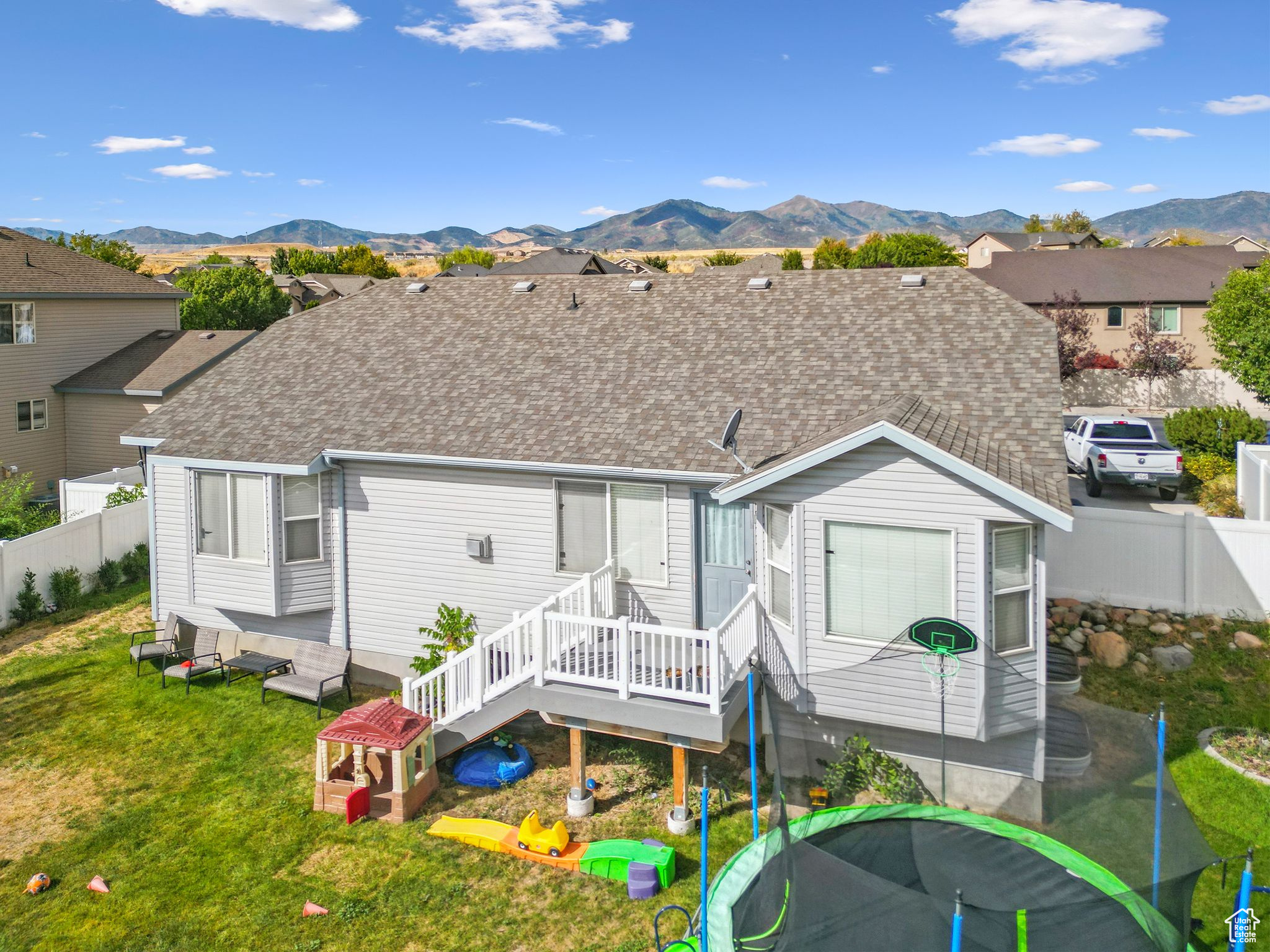 Back of property featuring a yard, fence, a deck with mountain view, and a shingled roof