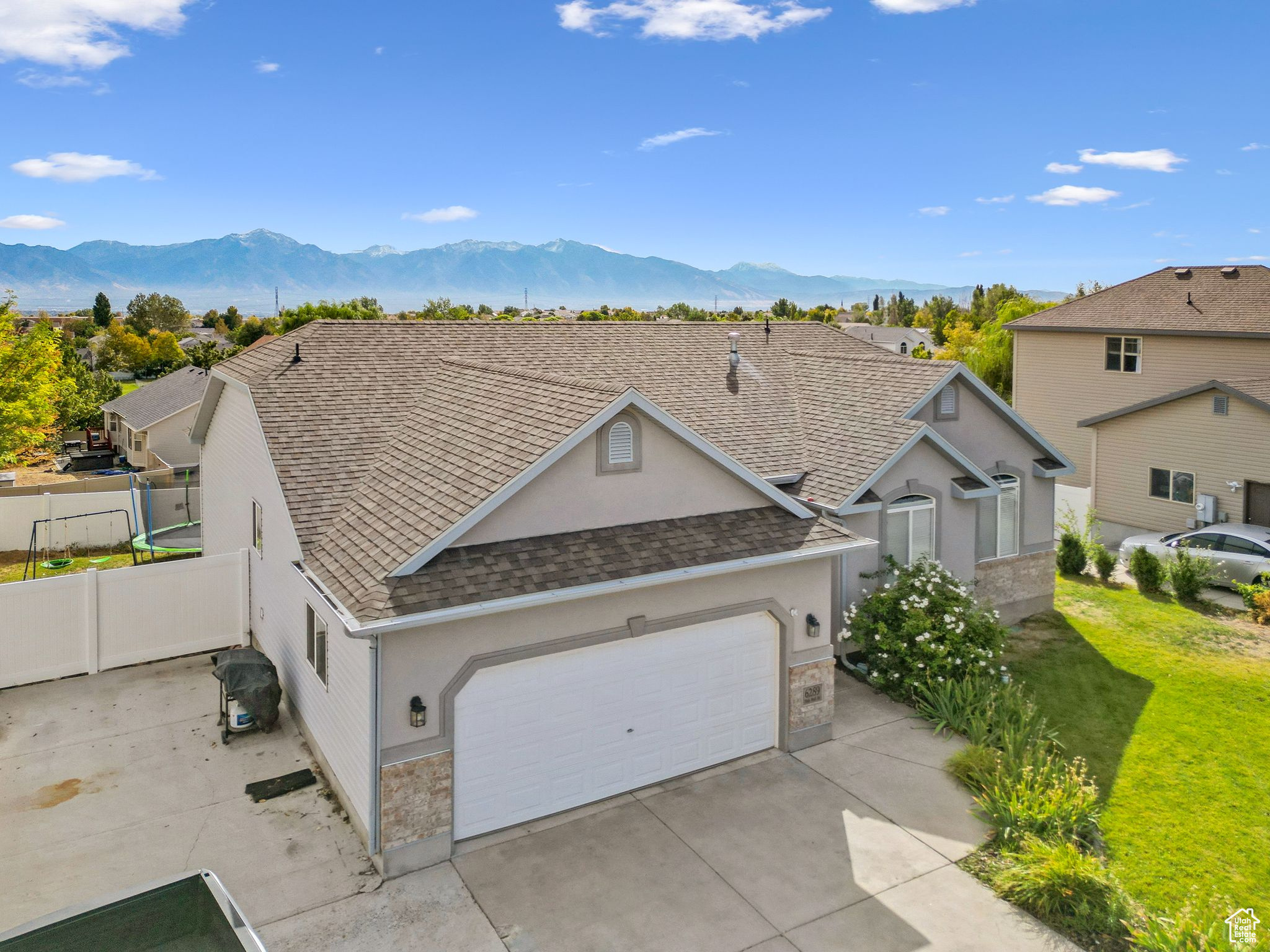 View of front facade featuring fence, concrete driveway, roof with shingles, a garage, and a mountain view