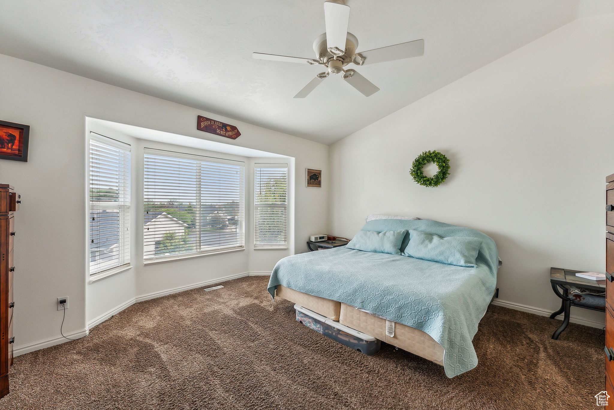Carpeted bedroom featuring lofted ceiling, a ceiling fan, baseboards, and visible vents