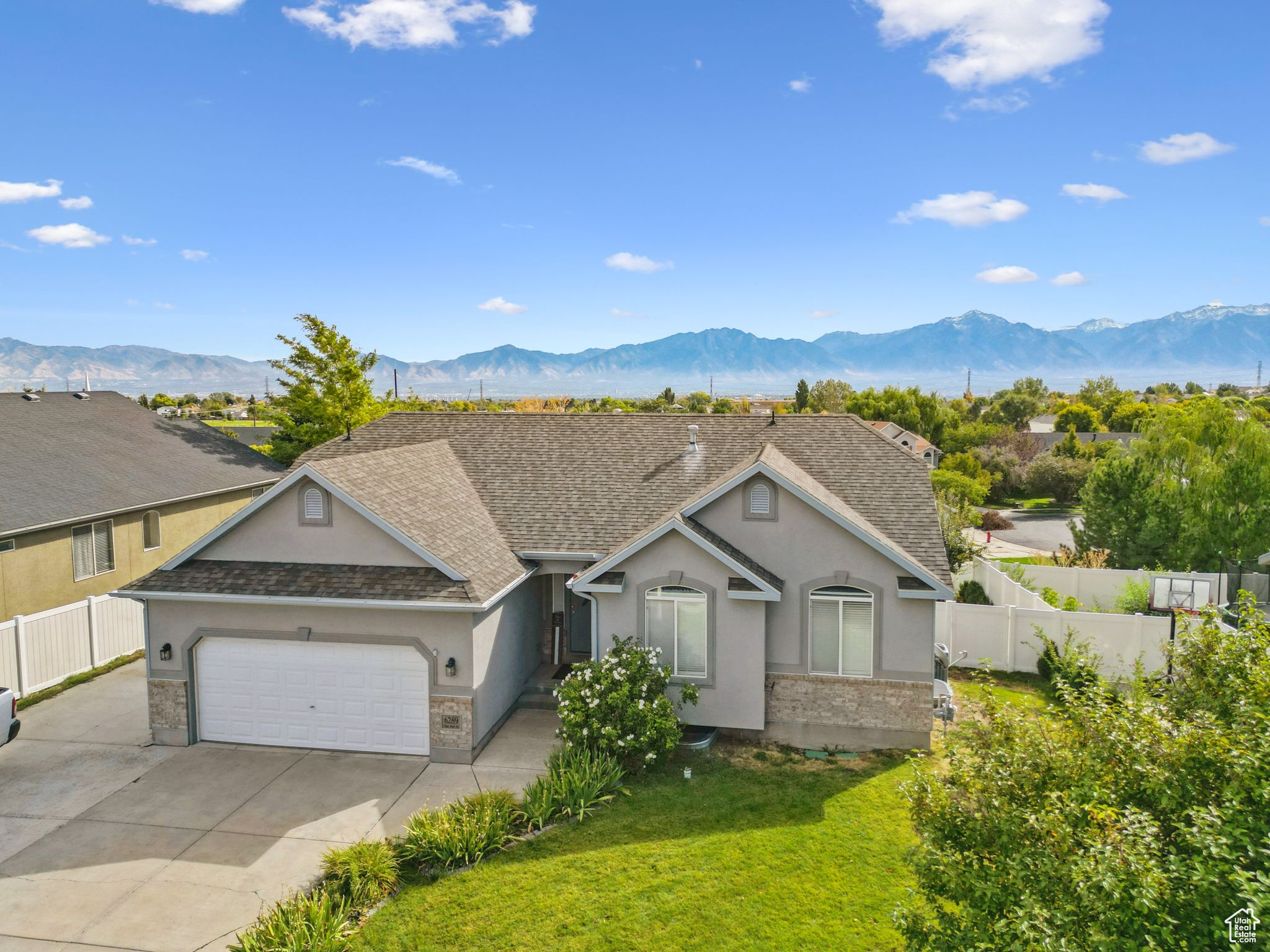 Single story home featuring stucco siding, a mountain view, an attached garage, and fence