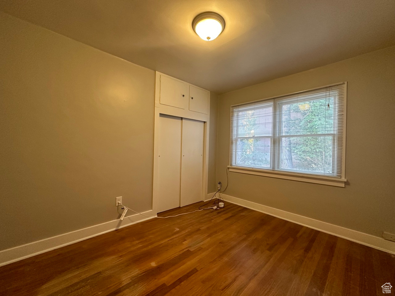Unfurnished bedroom featuring a closet, baseboards, and dark wood-type flooring