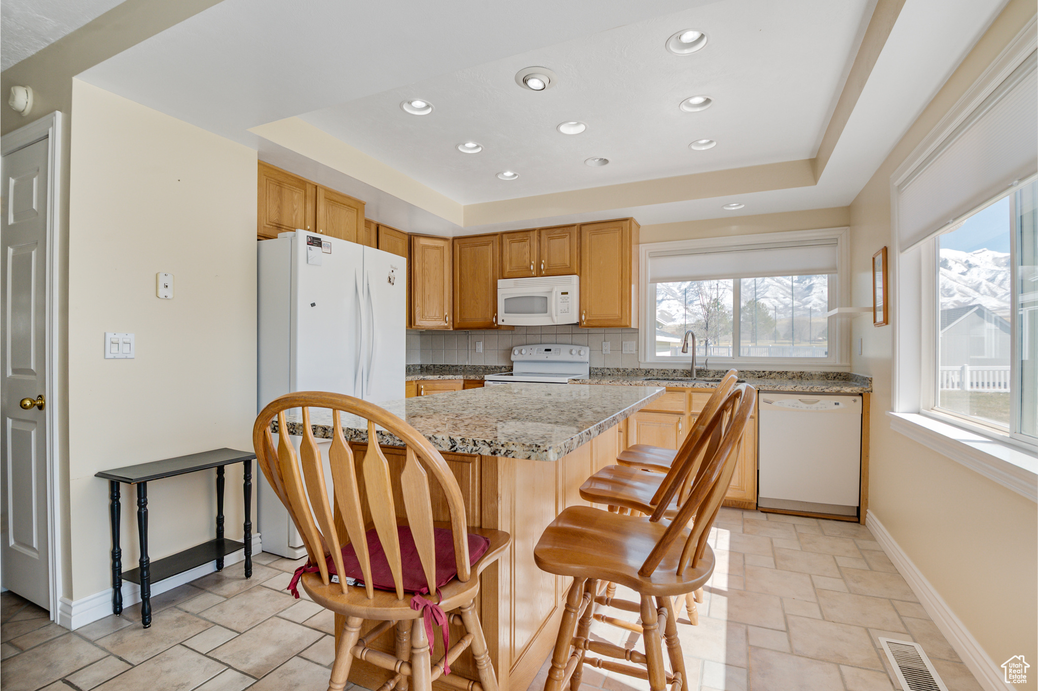 Kitchen featuring white appliances, visible vents, a sink, a raised ceiling, and tasteful backsplash