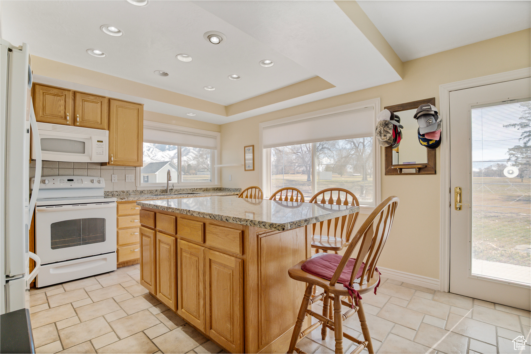 Kitchen with backsplash, light stone countertops & a breakfast bar
